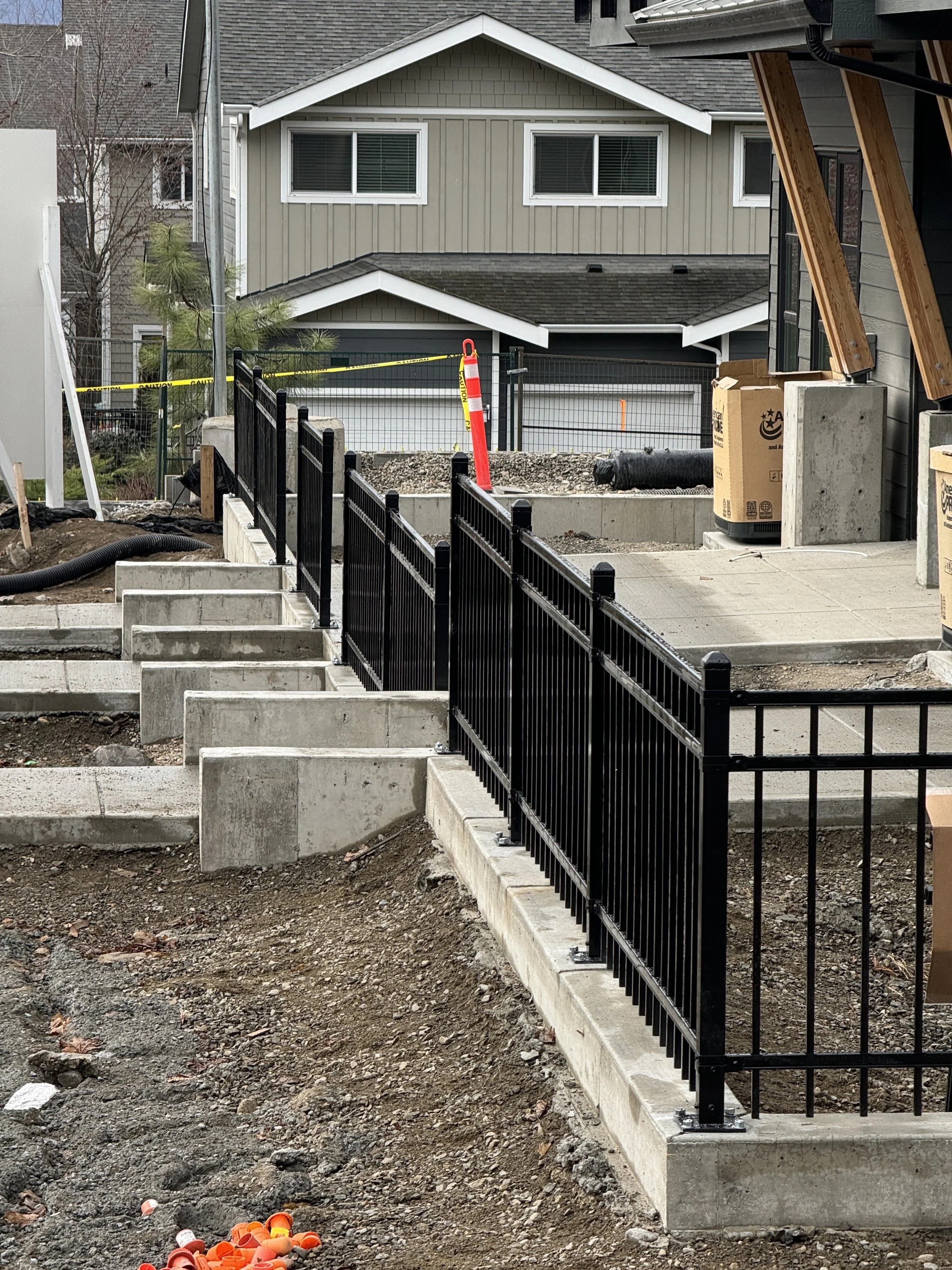 Construction site with new concrete stairs and black metal railing.