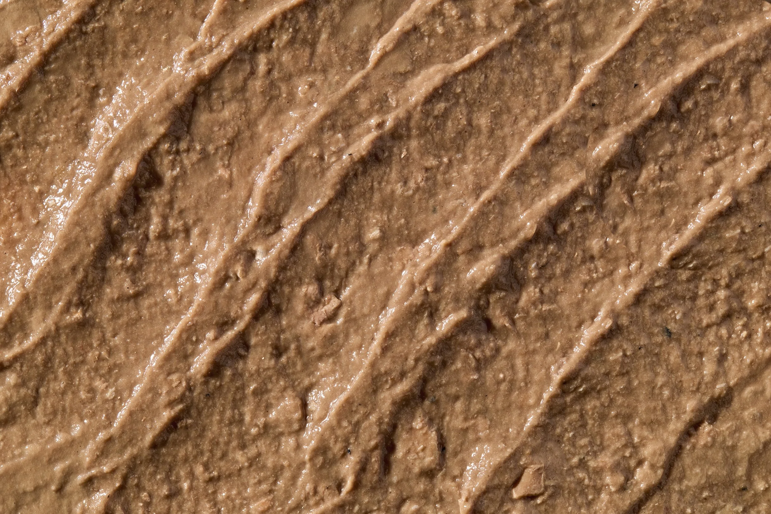 Close-up of a textured surface covered in brown frosting or chocolate spread with visible streaks.