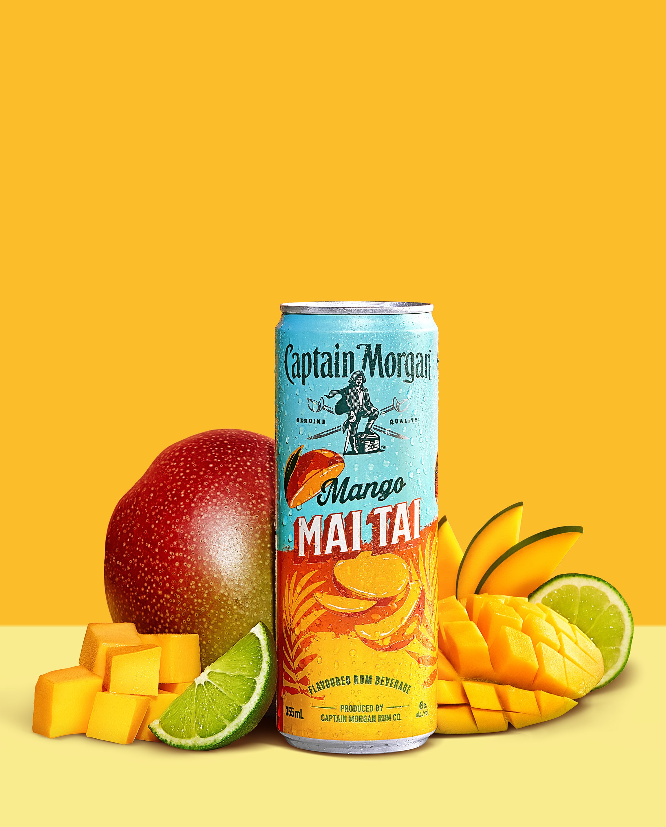 Captain Morgan Mango Maltai can with fresh mango, lime slices, and diced mango pieces on a yellow background.