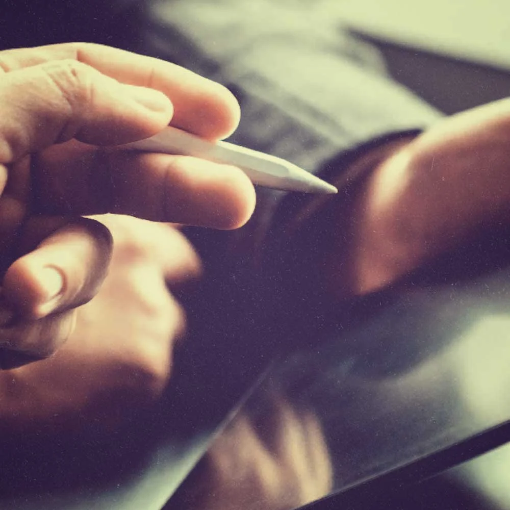 Hand in a sleeve of a business suit holding an apple pencil.