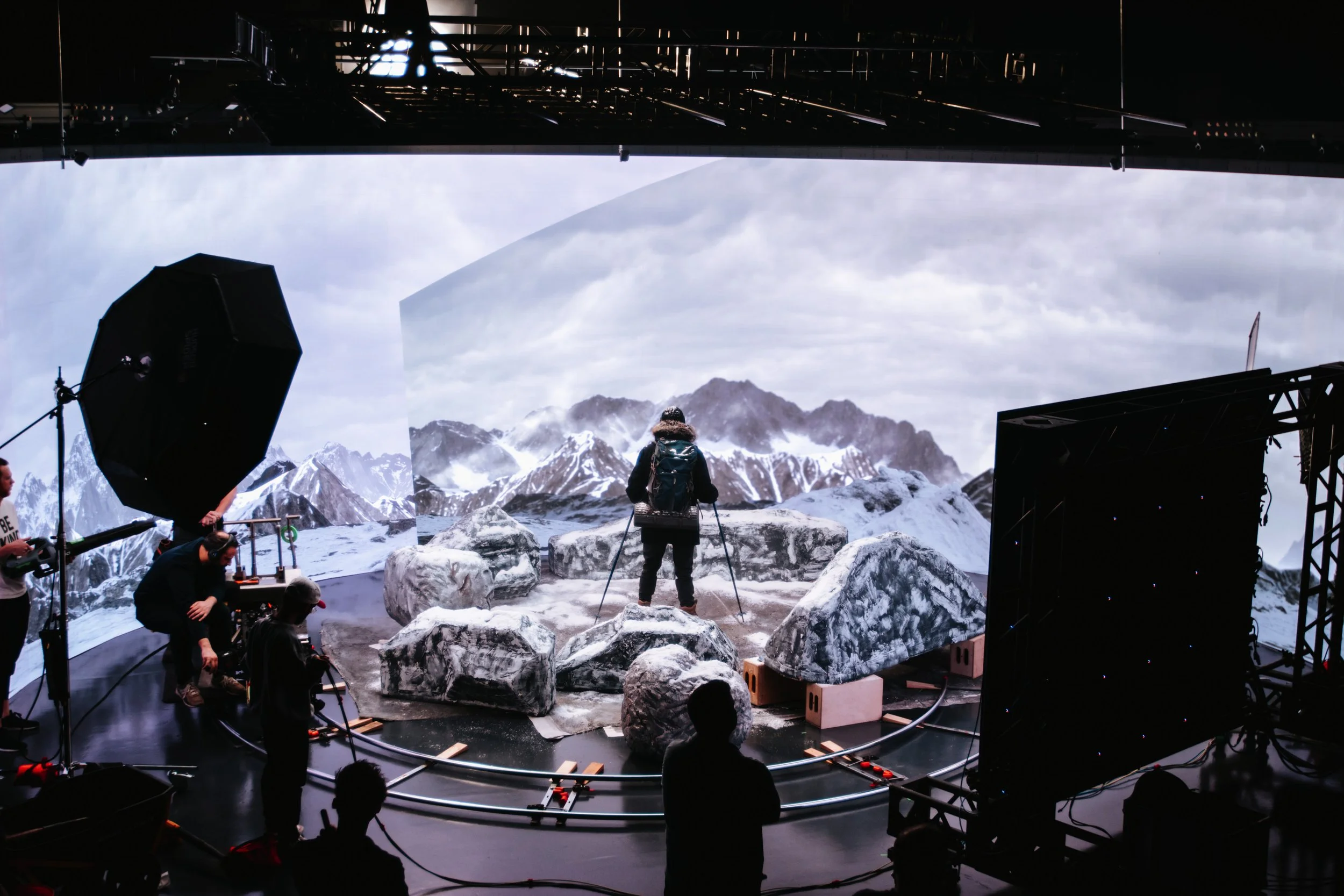 Actor performing scene on LED volume stage with snowy mountain environment background