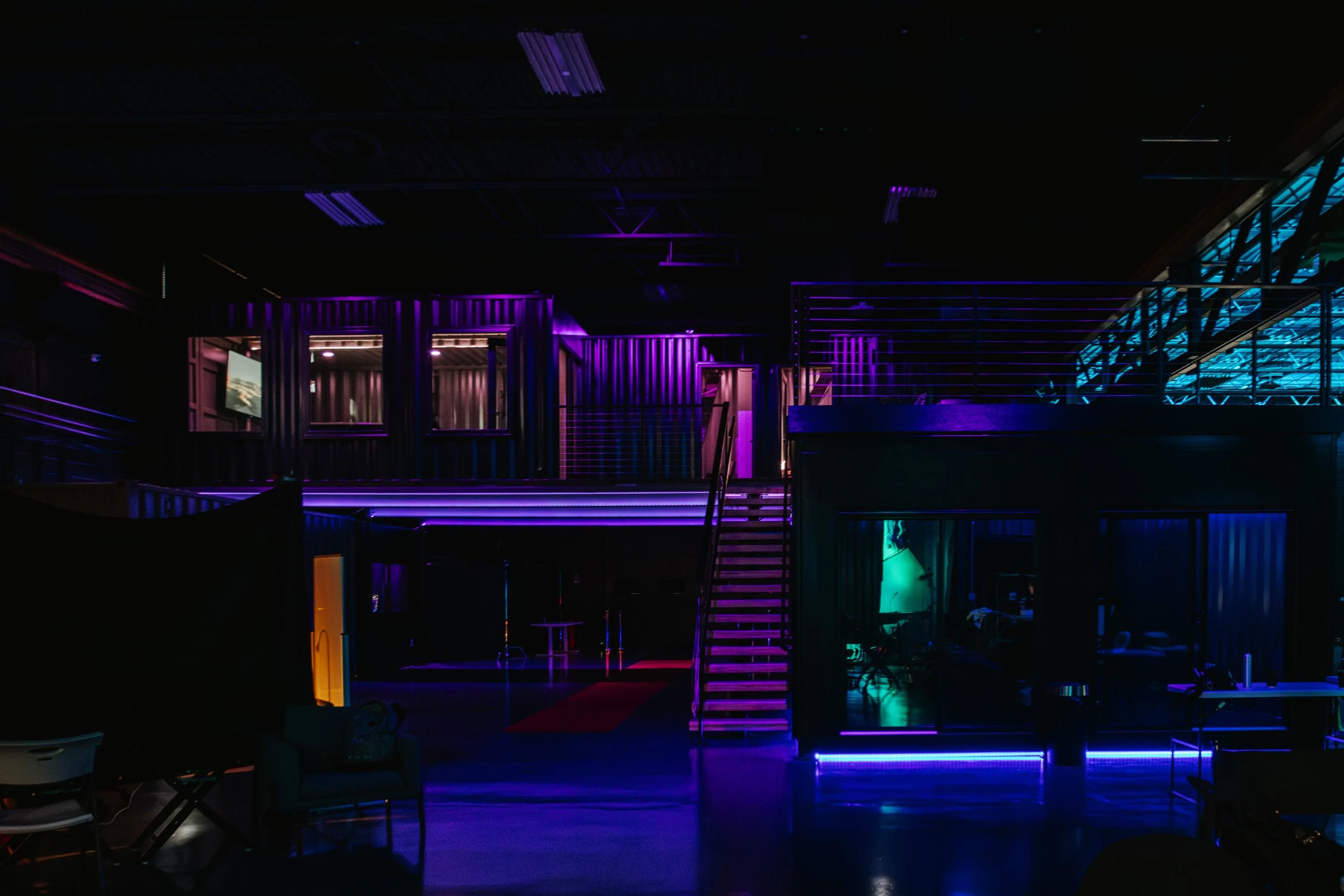 Photo of Golden Hour's shipping container hub featuring dark ambient lighting and LED lights illuminating sections of the space.