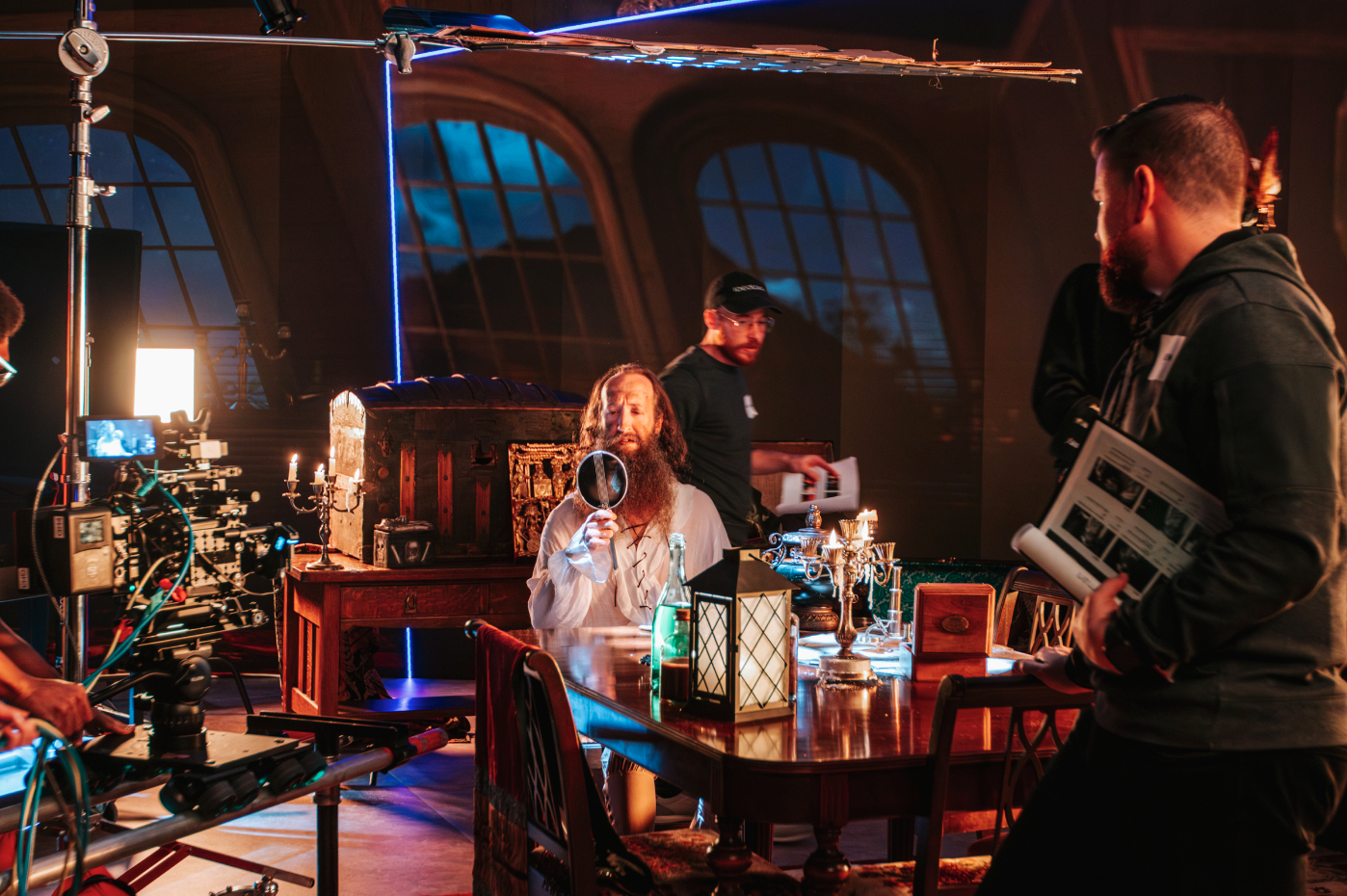 Actor on set in Golden Hour’s studio with props on a table, production equipment, and Golden Hour by IDEOLOGY staff visible in the shot.