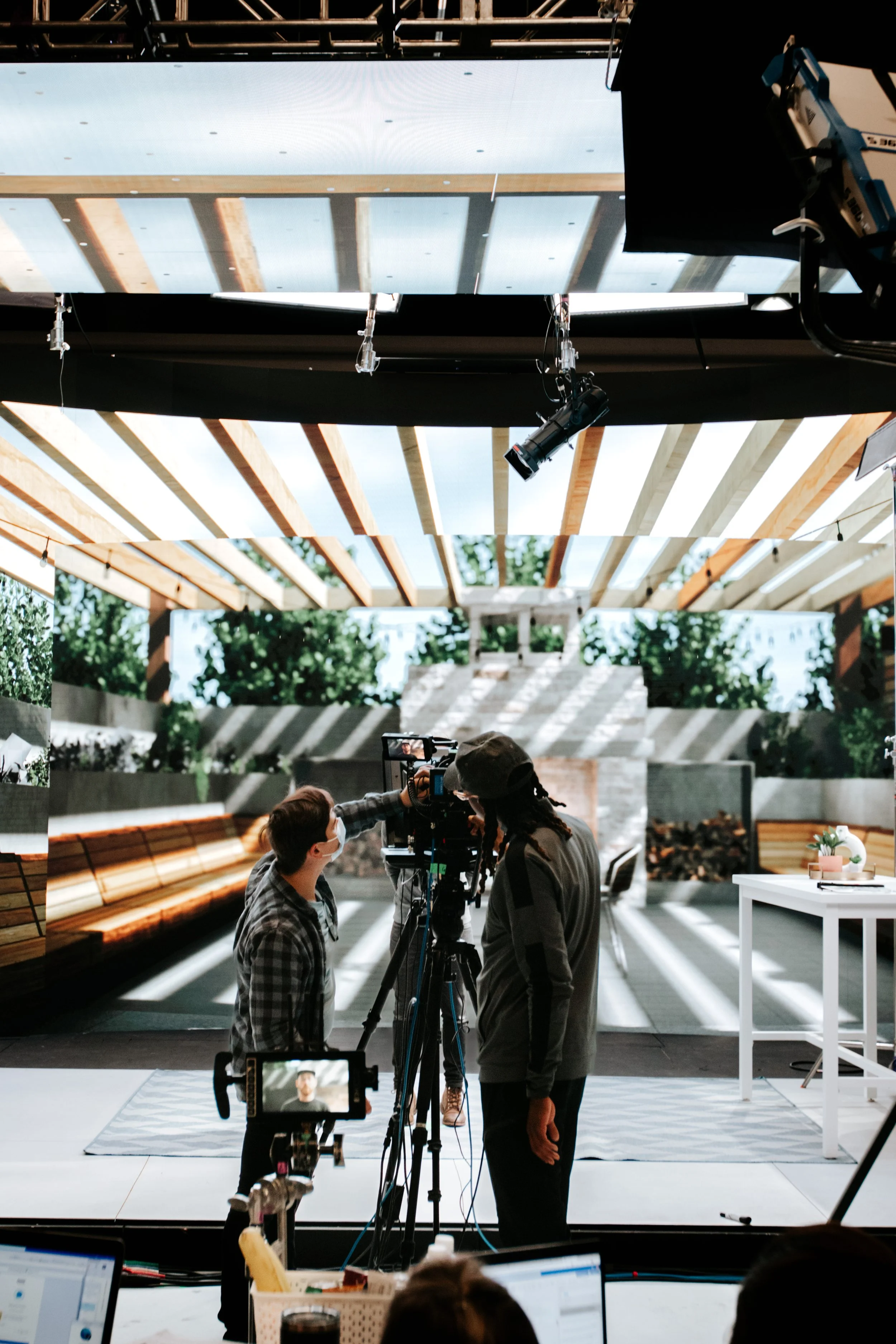 Behind-the-scenes photo of two people looking through a camera on set during a production shoot.
