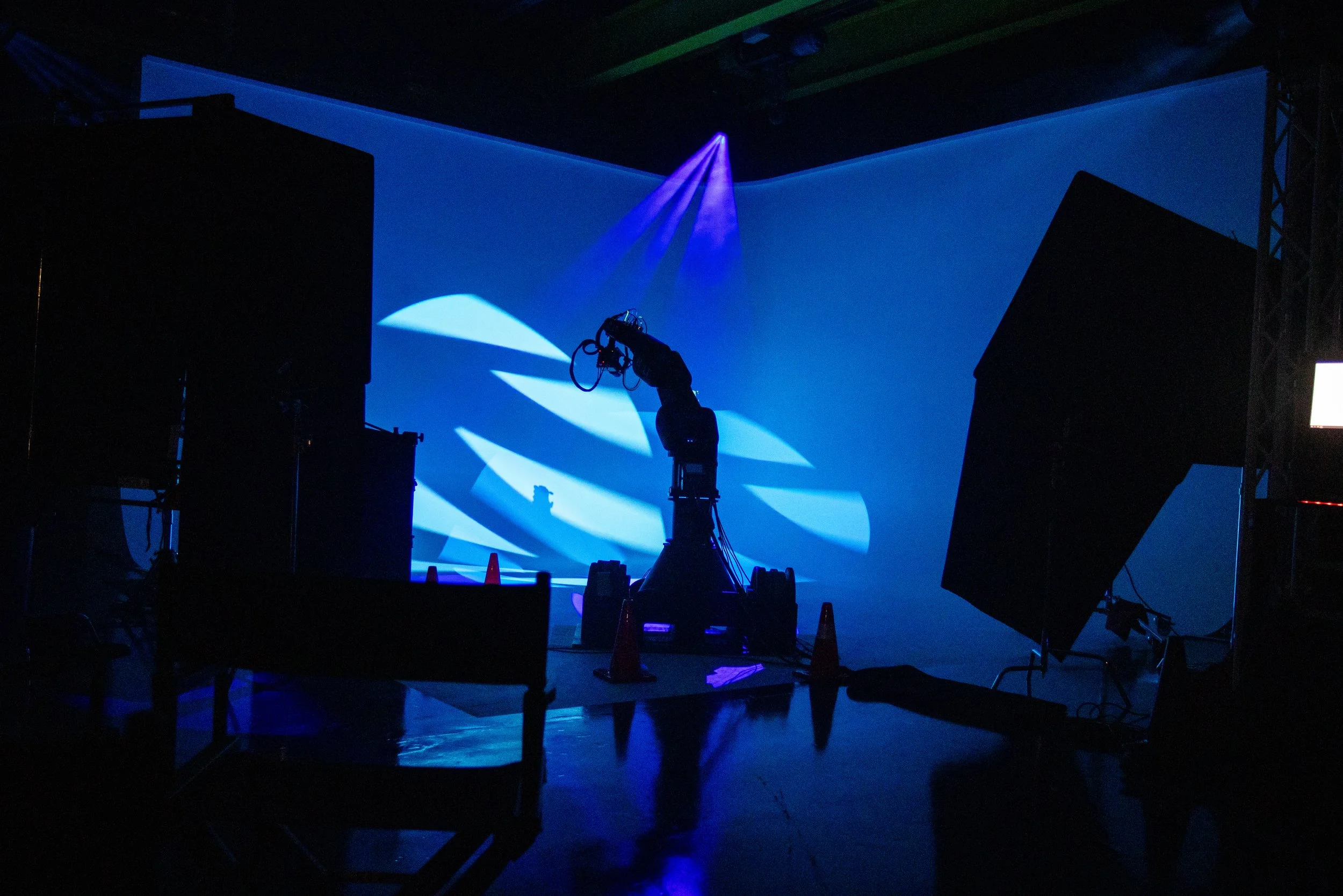 Behind-the-scenes photo of video production equipment at IDEOLOGY's Golden Hour studio with dark lighting and a blue illuminated background.