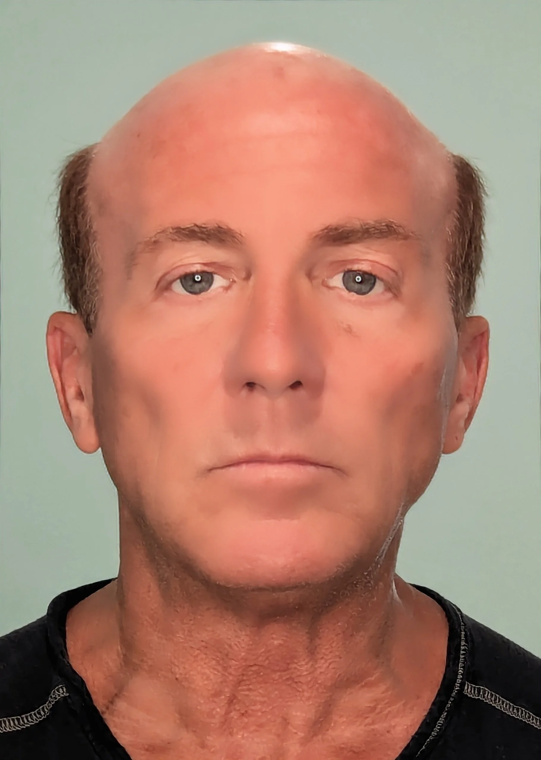 Close-up portrait of a man with a bald head, light skin, blue eyes, and wearing a black shirt, against a light green background.