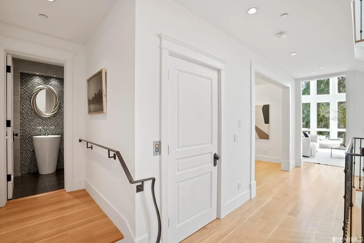 Hallway and stair landing renovation with white doors, custom trim, recessed lights, wide-plank hardwood flooring, and powder room with mosaic tile—San Francisco Bay Area general contractor Pinnacle Construction.