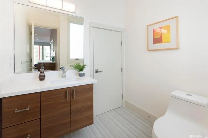 Bathroom vanity area in San Francisco Bay Area condo remodel with wood cabinetry and bright white finishes — general contractor