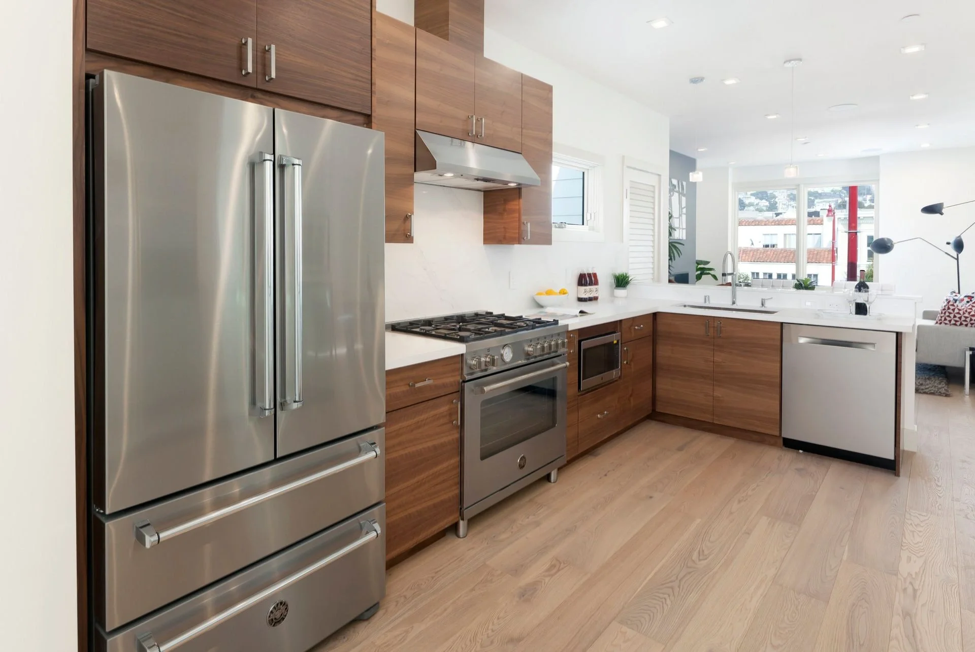 Condo kitchen renovation with stainless refrigerator, wood cabinets, and wide-plank flooring — San Francisco Bay Area general contractor