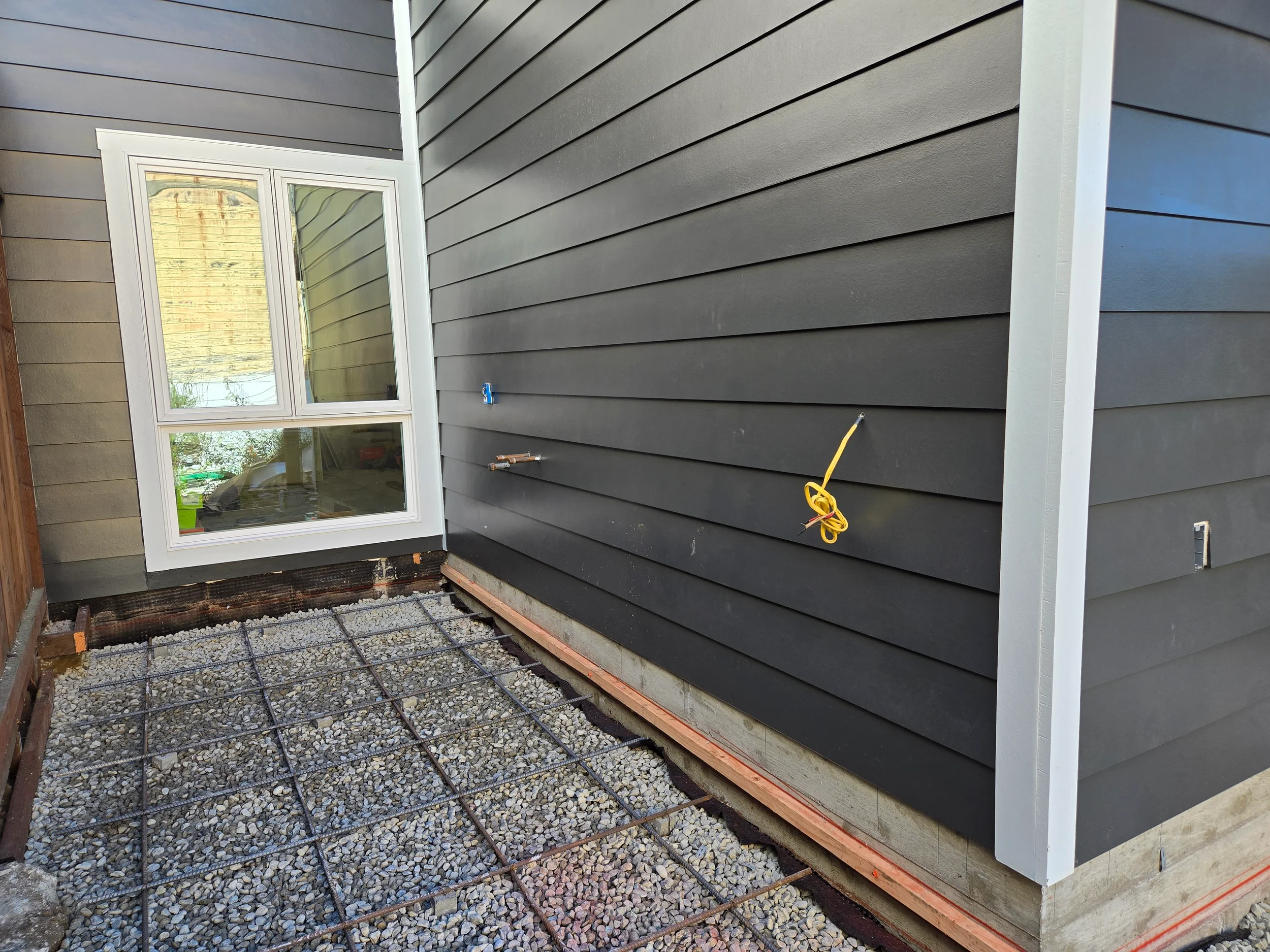 Exterior corner finish with new siding and gravel base during ground-floor conversion — San Francisco Bay Area general contractor