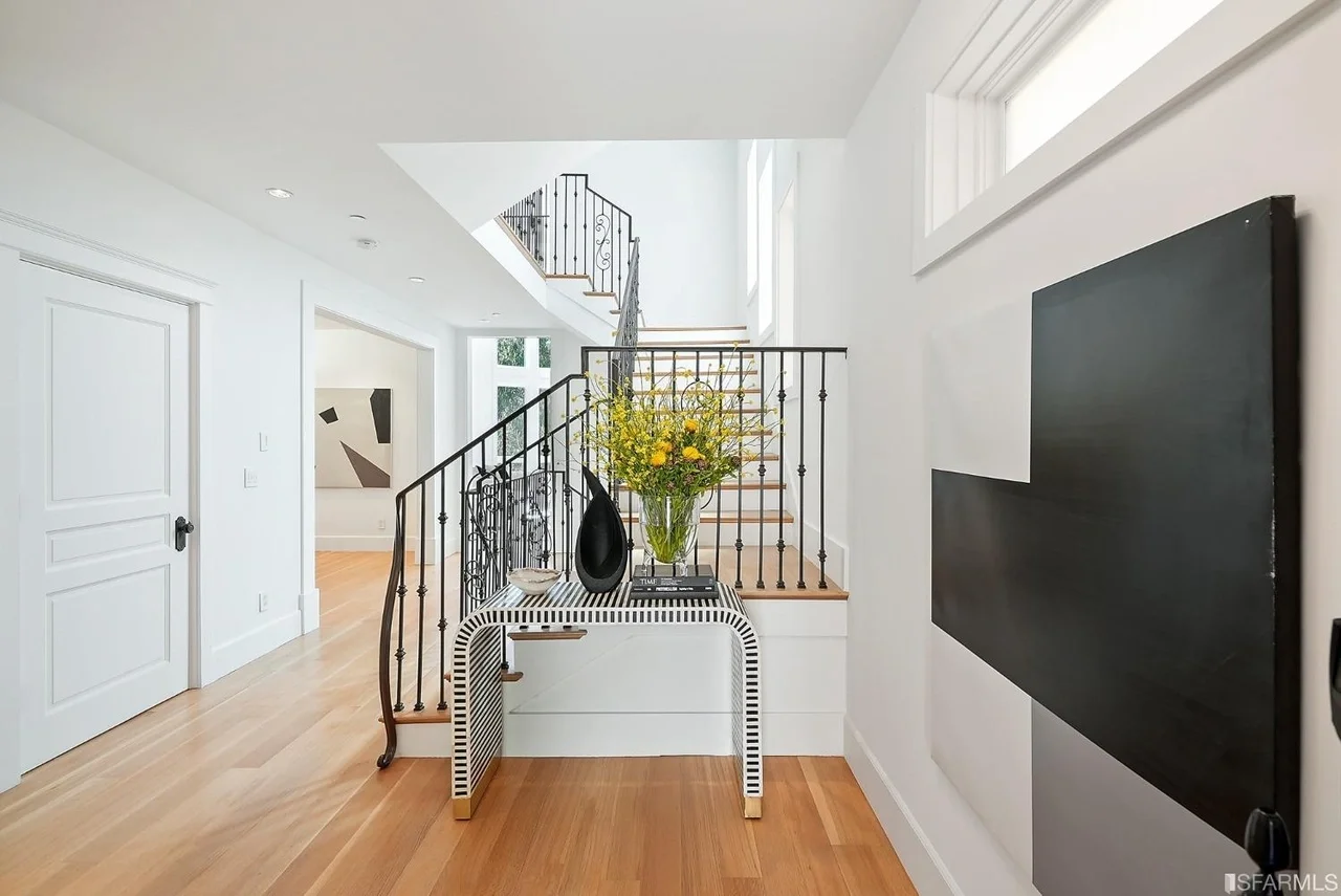 Modern foyer renovation with wood staircase, wrought-iron railing, white walls, and hardwood flooring—San Francisco Bay Area general contractor Pinnacle Construction