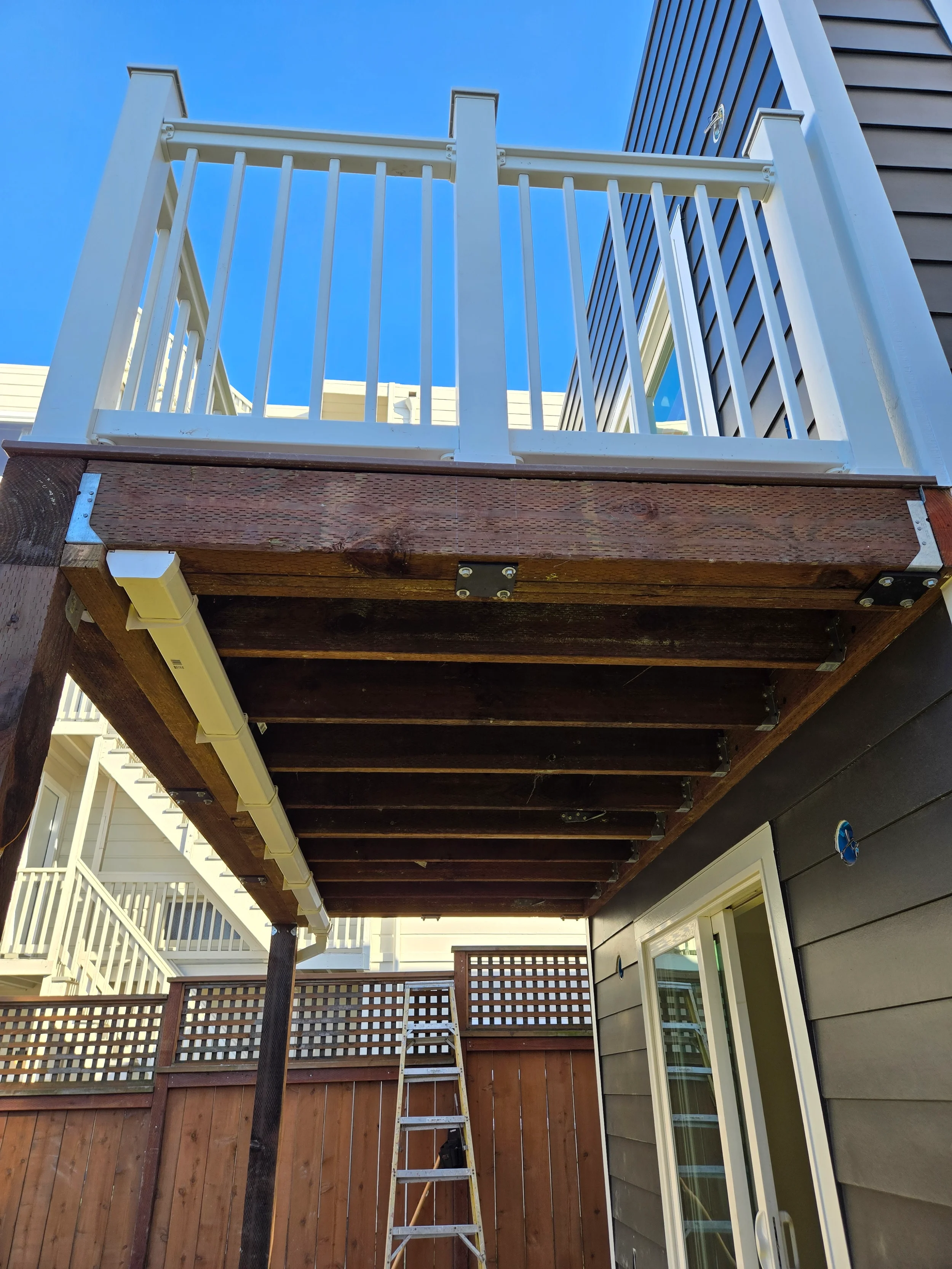 Underside deck framing during ground-floor conversion showing joists and structural beams — San Francisco Bay Area general contractor