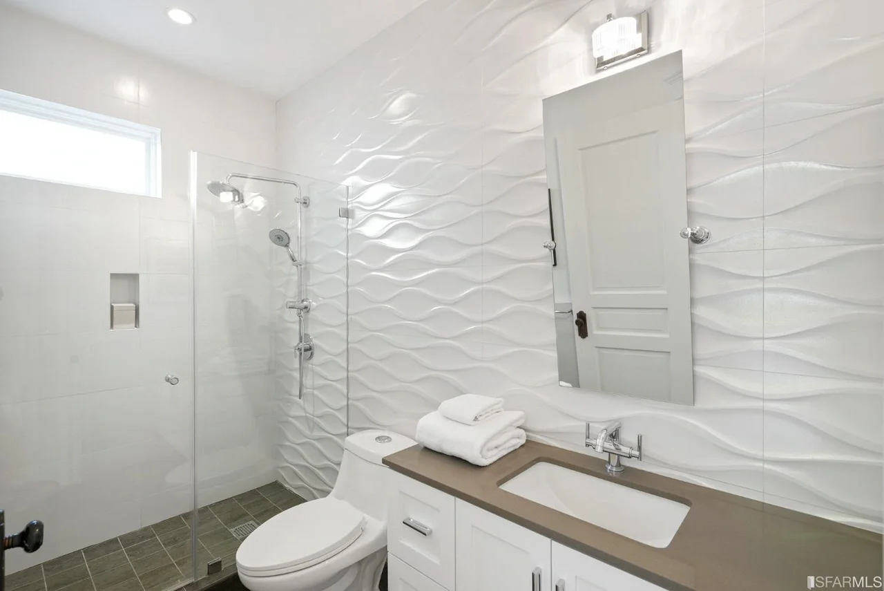 Bathroom renovation with white tile, glass shower enclosure, and modern vanity — San Francisco Bay Area general contractor.