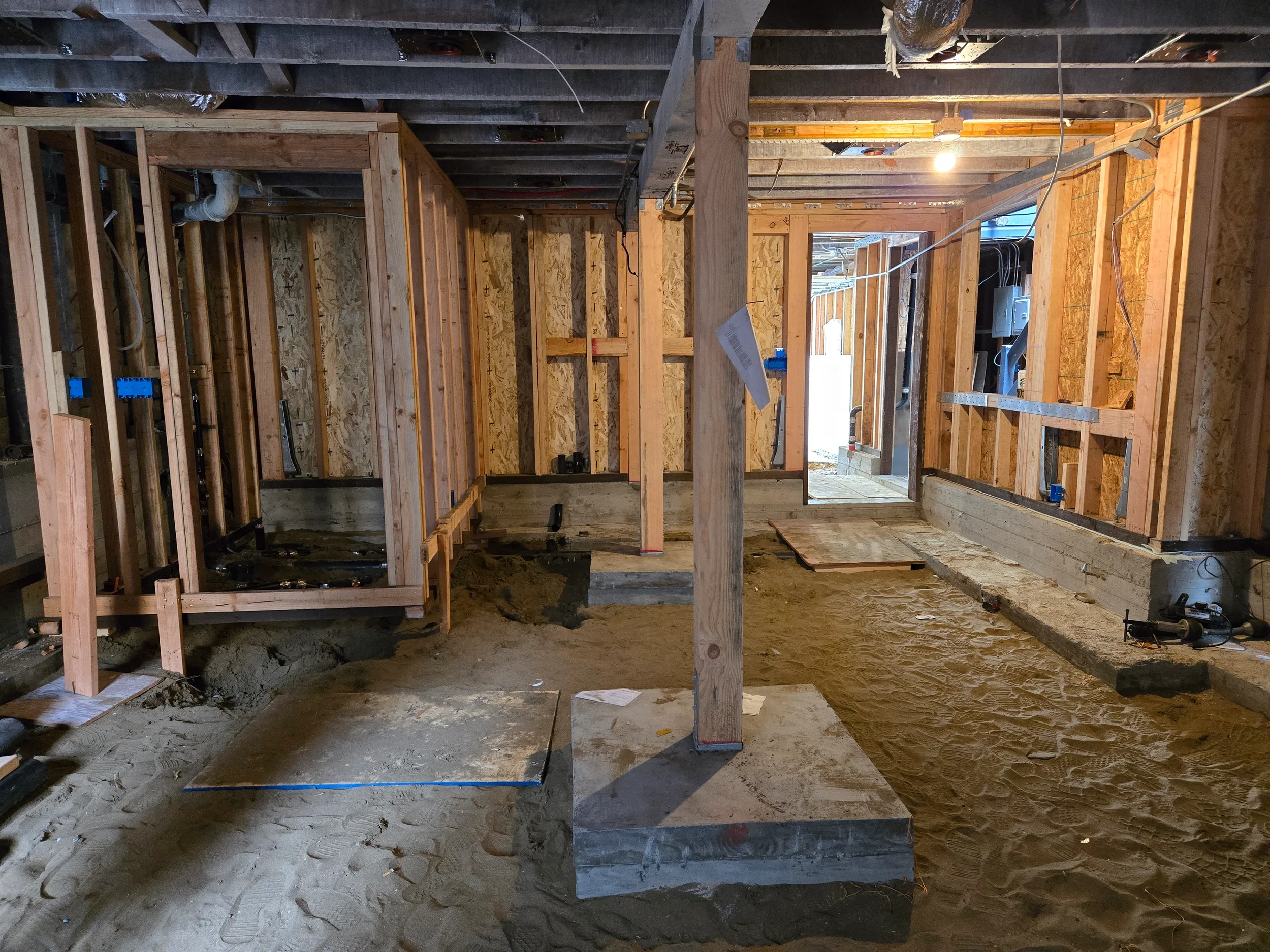 Crawlspace corridor with posts and framing during ground-floor conversion in progress — San Francisco Bay Area general contractor