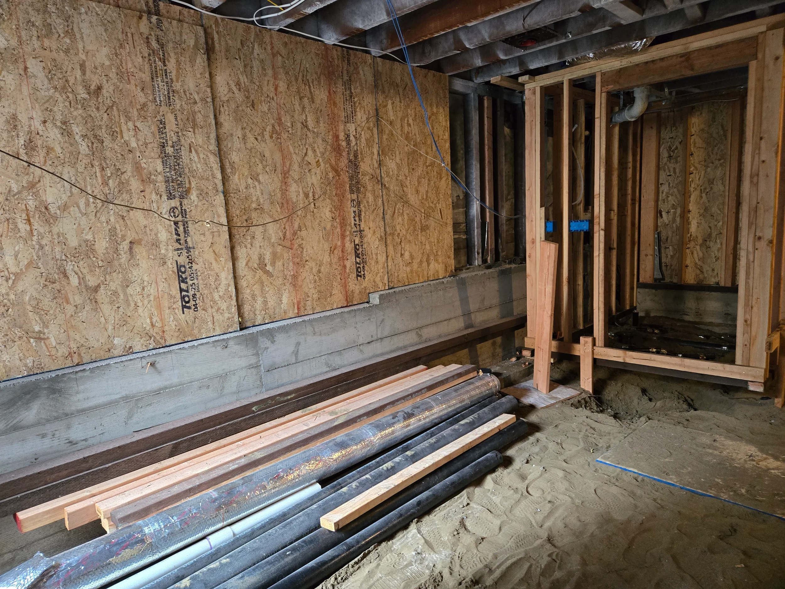 Plumbing and mechanical runs under floor during ground-floor conversion build-out — San Francisco Bay Area general contractor