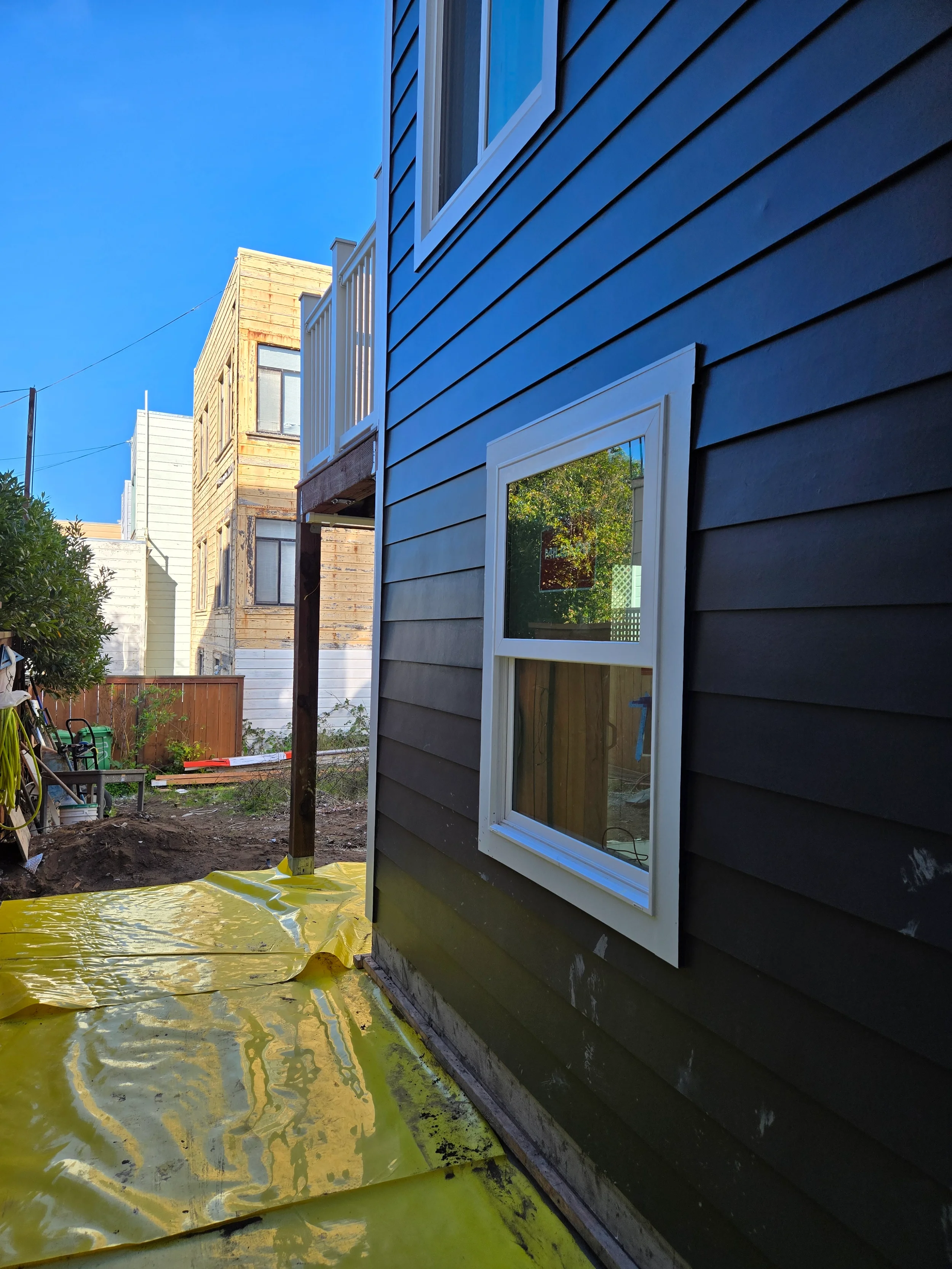 Side yard exterior during ground-floor conversion with new siding and narrow walkway — San Francisco Bay Area general contractor