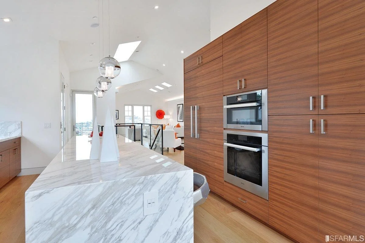 kitchen with custom wood cabinet wall, built-in ovens, and stone counters — San Francisco Bay Area general contractor