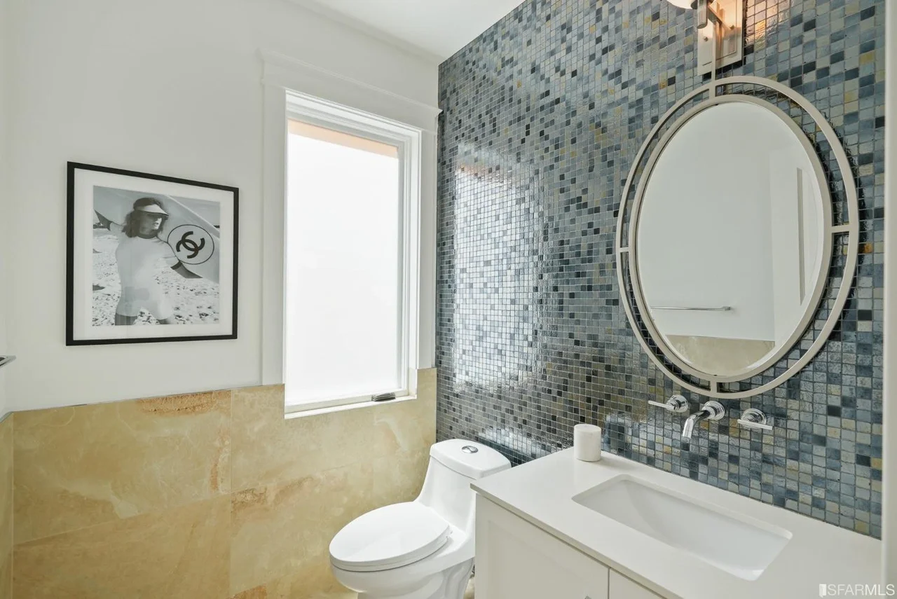 Bathroom renovation with mosaic tile wall, round mirror, and pedestal sink — San Francisco Bay Area general contractor.