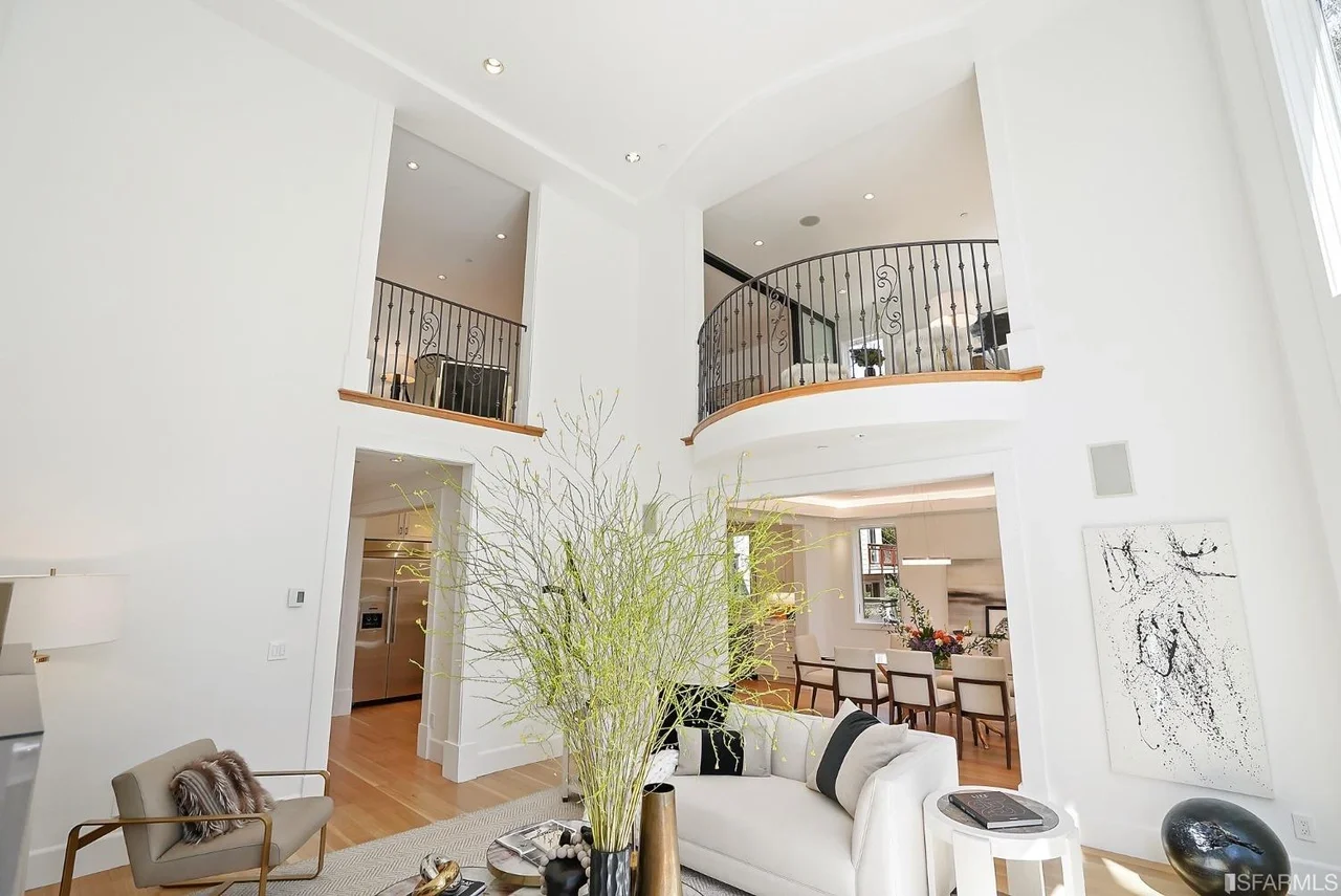 Bright entryway remodel with custom staircase, black iron railing, and wide-plank hardwood flooring