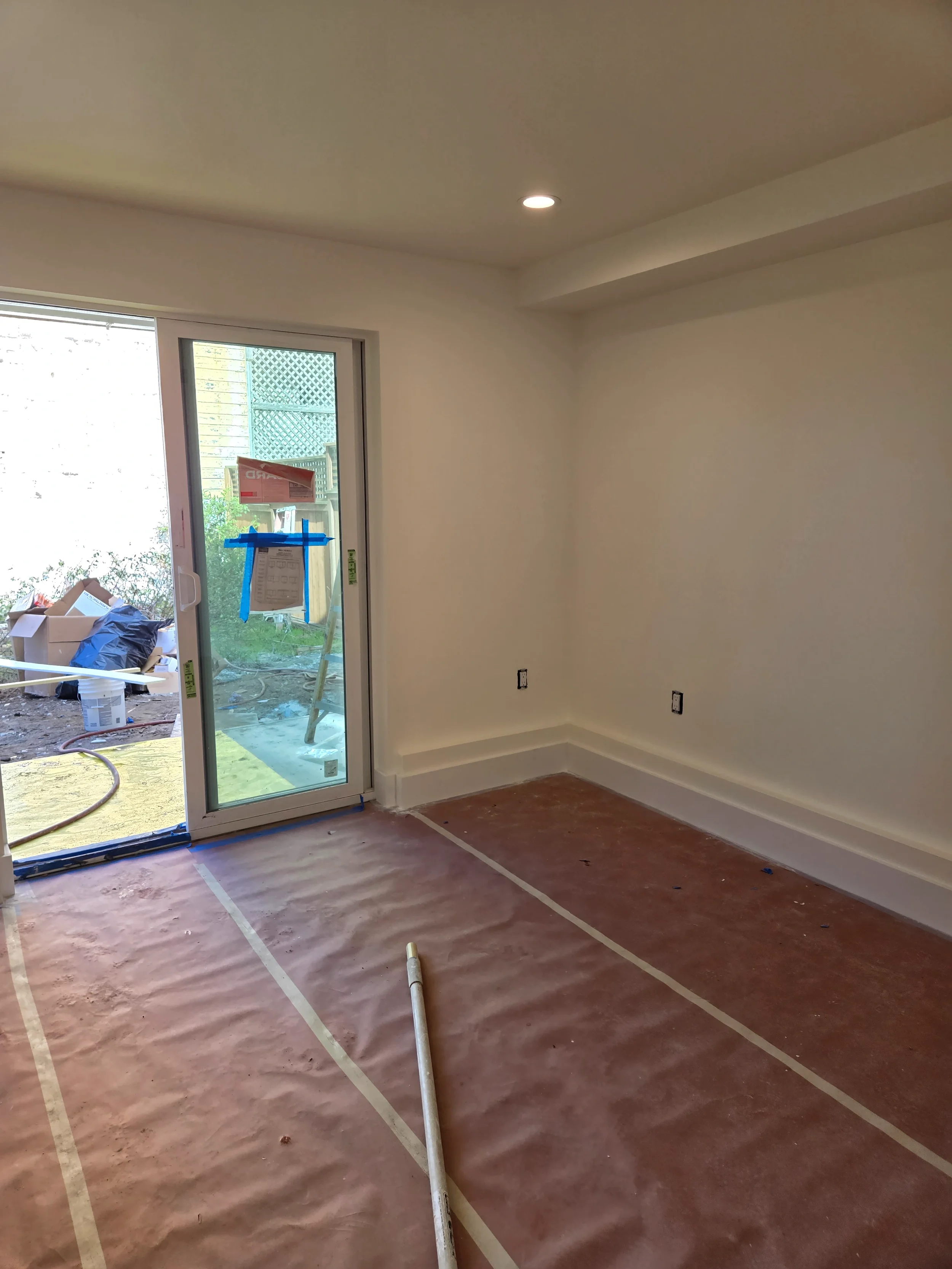 Ground-floor room nearing finish with new door to yard and updated wall surfaces — San Francisco Bay Area general contractor
