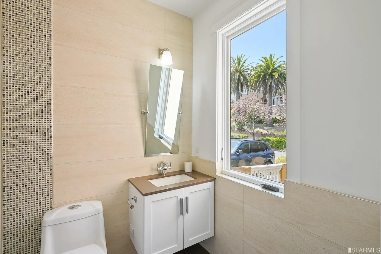 Bathroom vanity remodel with modern mirror and bright window — San Francisco Bay Area general contractor.