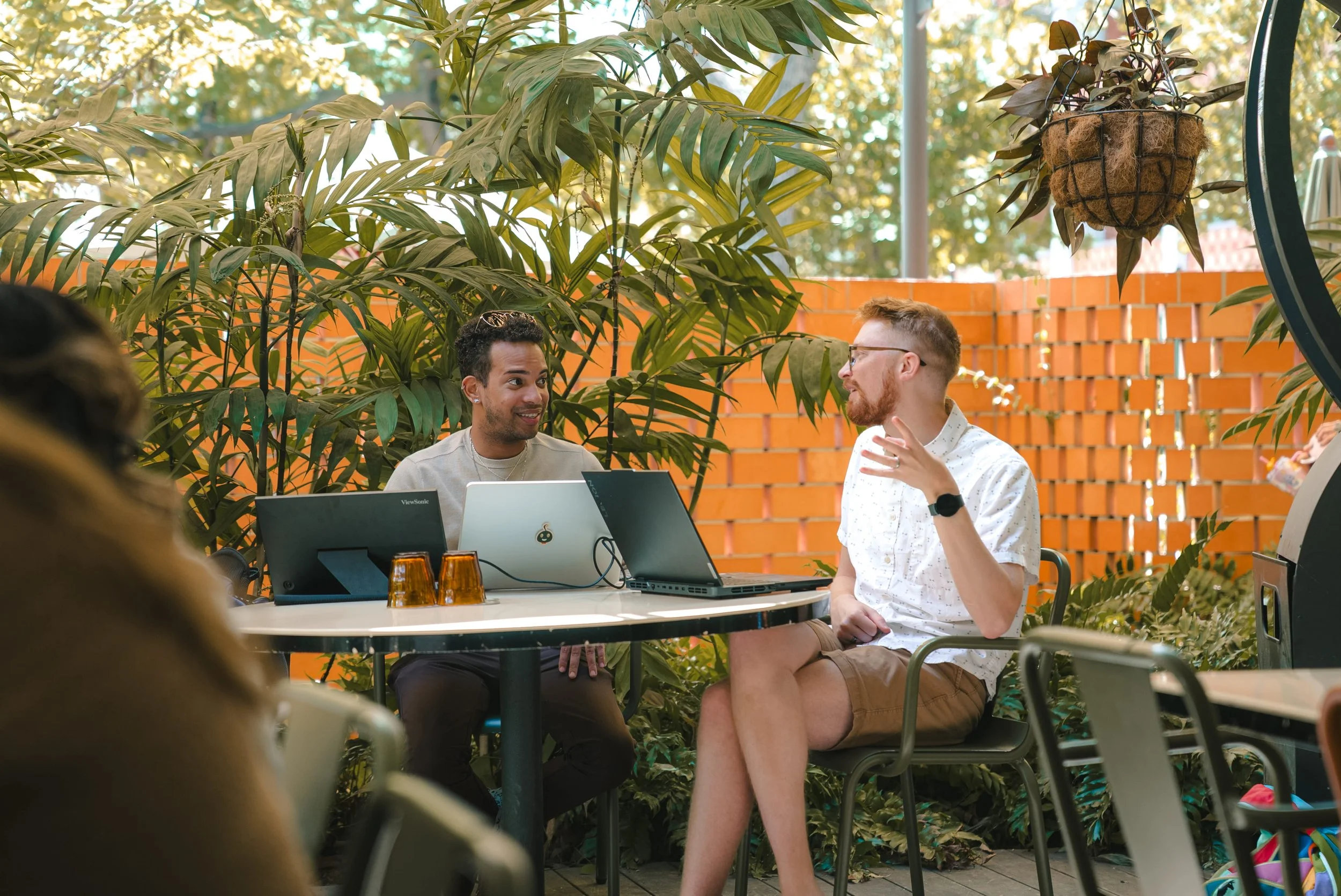 Vineskills team members Danger and Jacob collaborating at our team retreat in April 2026.  There are laptops and drinks on the table.