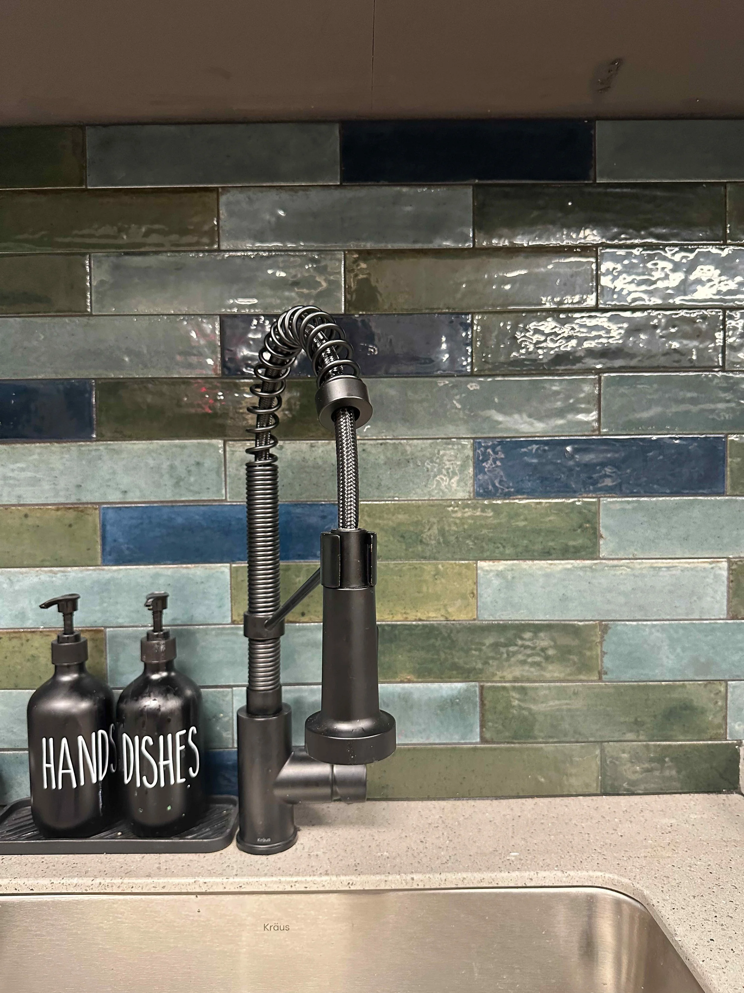 Break room kitchen detail with multicolor green and blue zellige tile backsplash, matte black industrial spring faucet, and quartz countertop, interior design by Luxe Style Studio