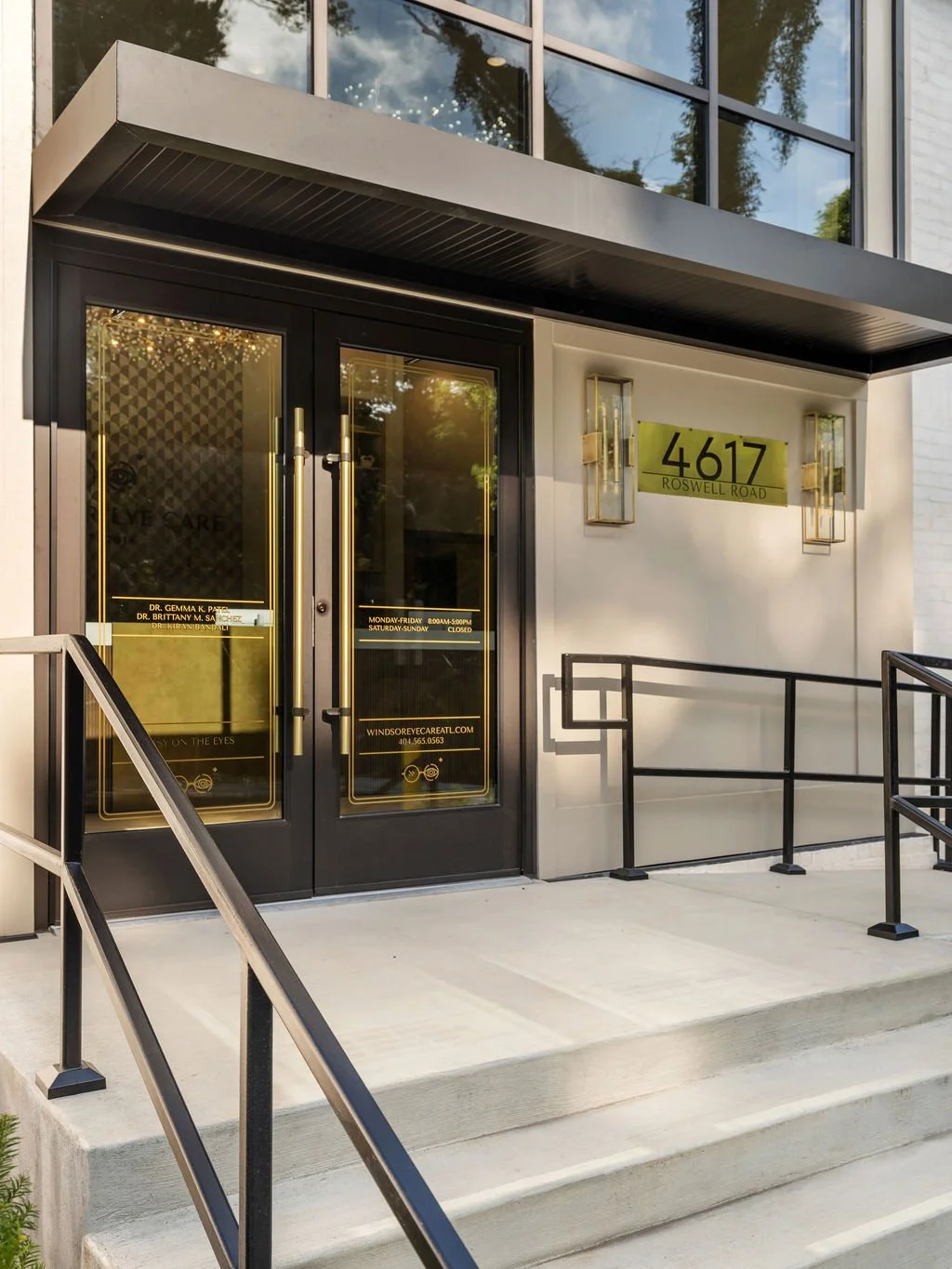 Luxury commercial entry with black steel and glass doors, brass pull hardware, and gold address signage at 4617 Roswell Road Atlanta, interior design by Luxe Style Studio