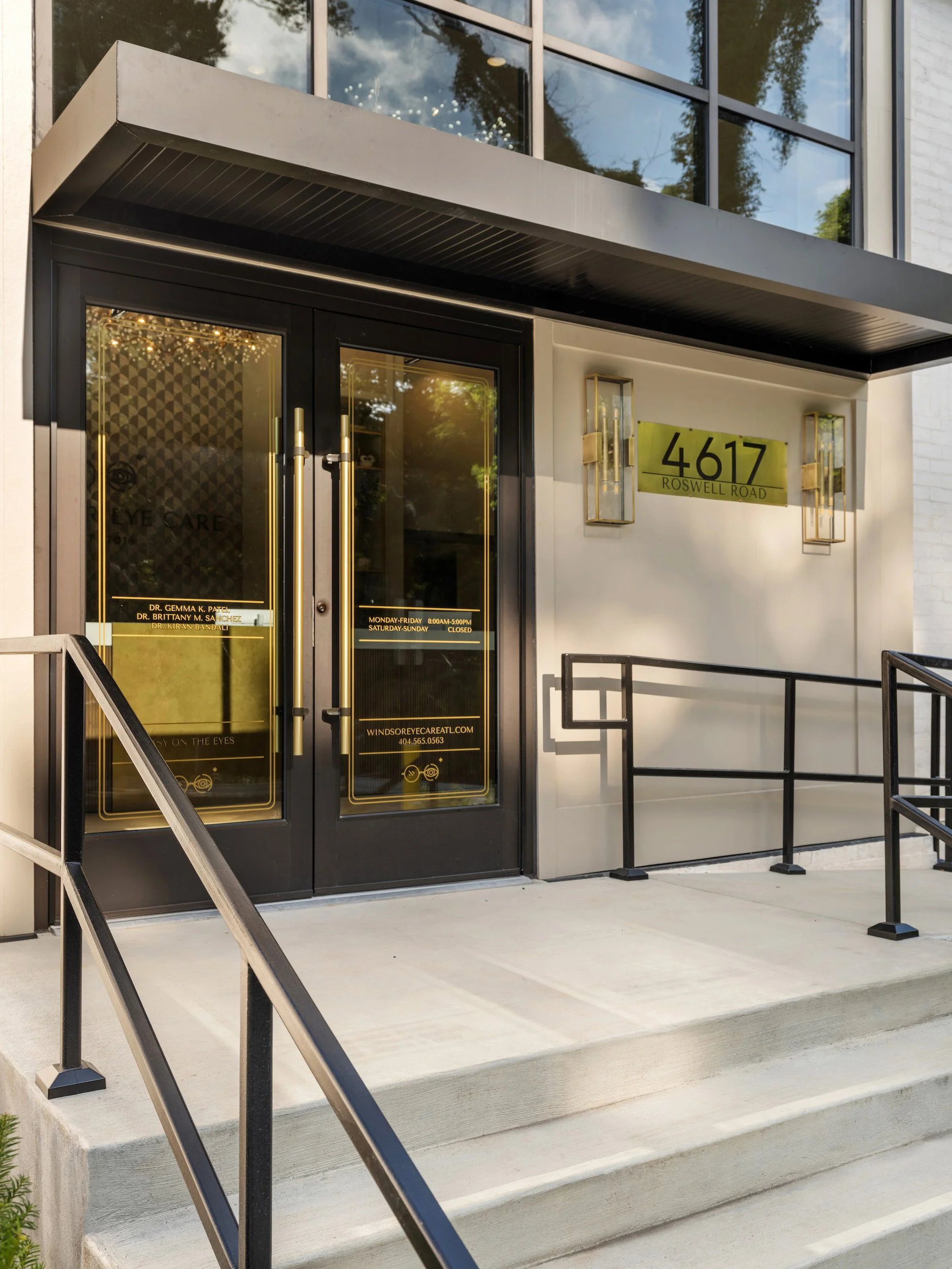 Black steel-and-glass entry doors with brass pulls and Windsor Eye Care signage, designed by Luxe Style Studio