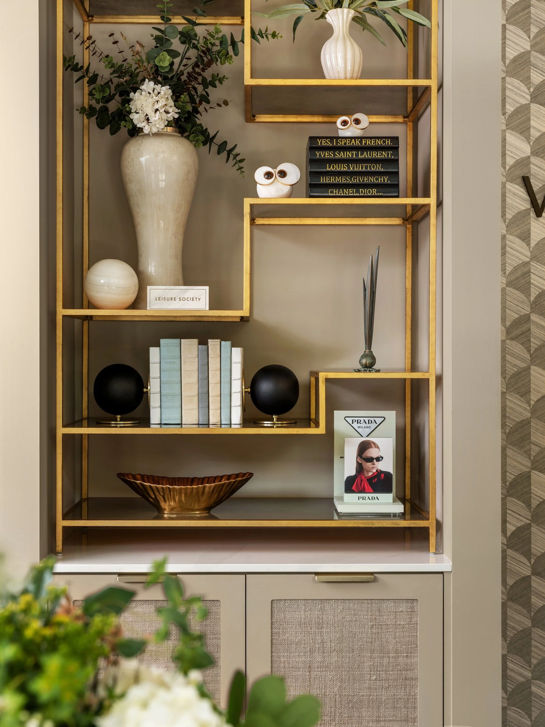 Styled gold brass open shelving unit with ceramic vases, decorative books, and sculptural objects in luxury commercial interior, Windsor Eye Care optical boutique, Atlanta, GA, interior design by Luxe Style Studio