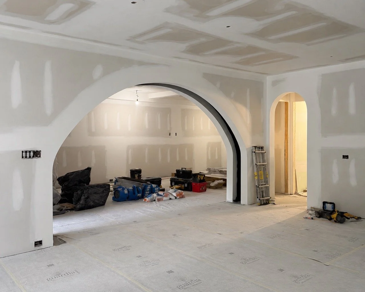 Interior renovation under construction with newly formed arches and coordinated ceiling details for a Luxe Style Studio project