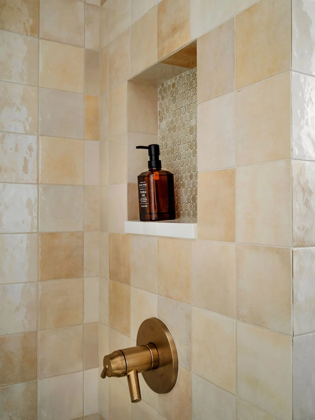 Shower niche detail with warm cream zellige field tile, penny tile niche accent, and brushed brass shower valve, interior design by Luxe Style Studio