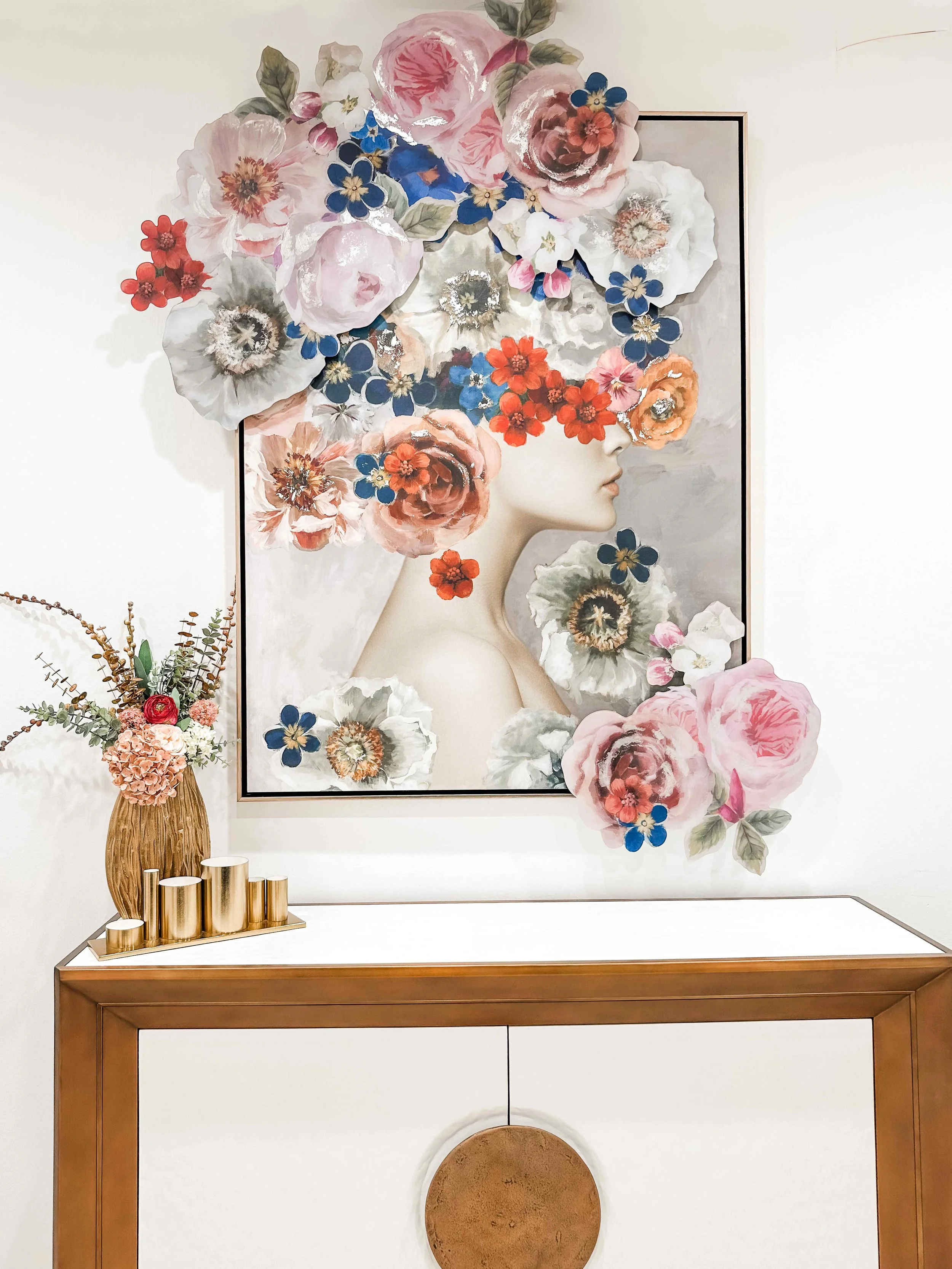 Medical spa reception area featuring oversized dimensional floral portrait wall art, gold and white console table, and brass cylinder candleholders, interior design by Luxe Style Studio
