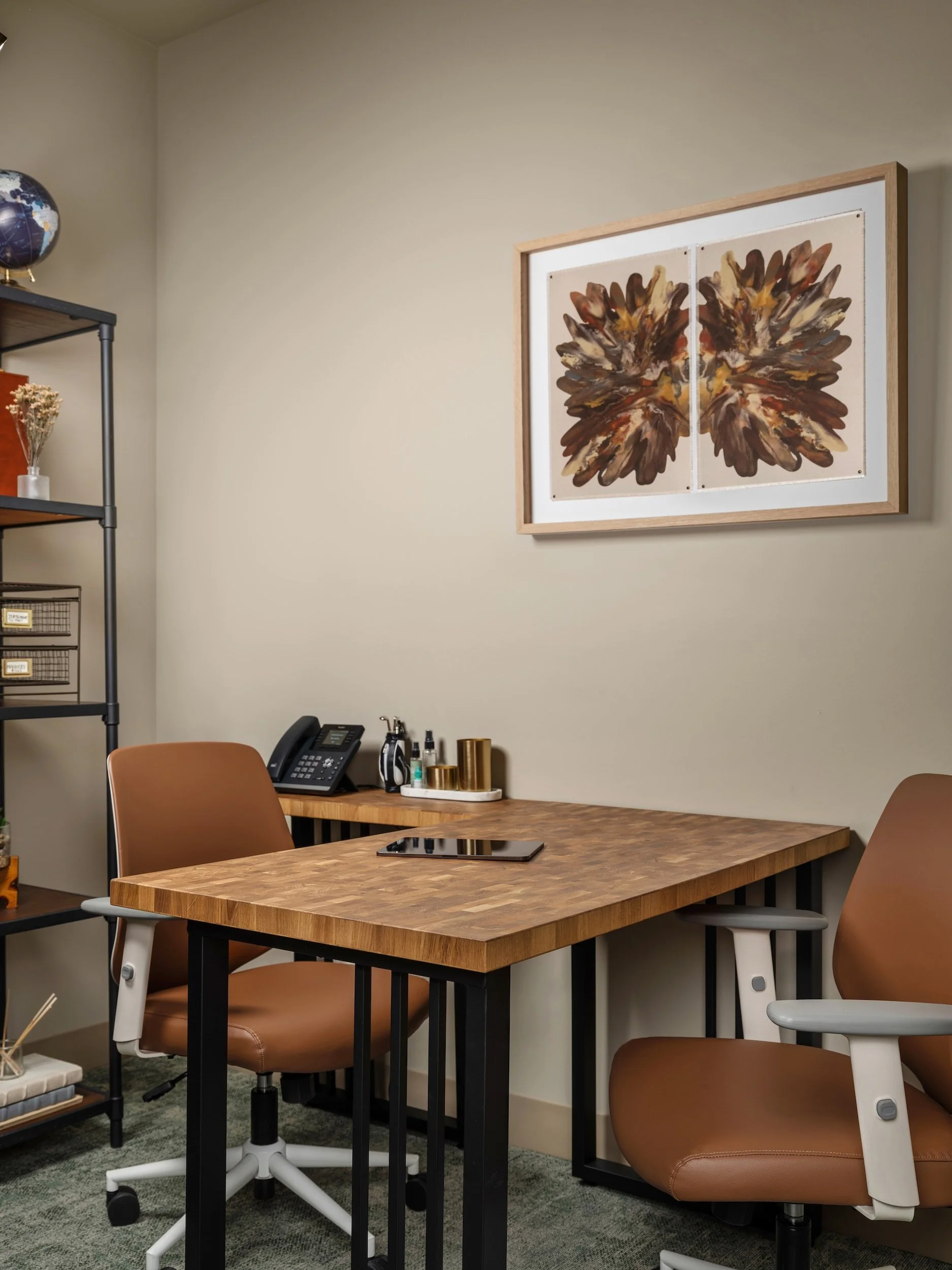 Private consultation office with butcher block desk, cognac leather task chairs, industrial shelving, and abstract botanical framed artwork, Windsor Eye Care optical boutique, Atlanta, GA, interior design by Luxe Style Studio