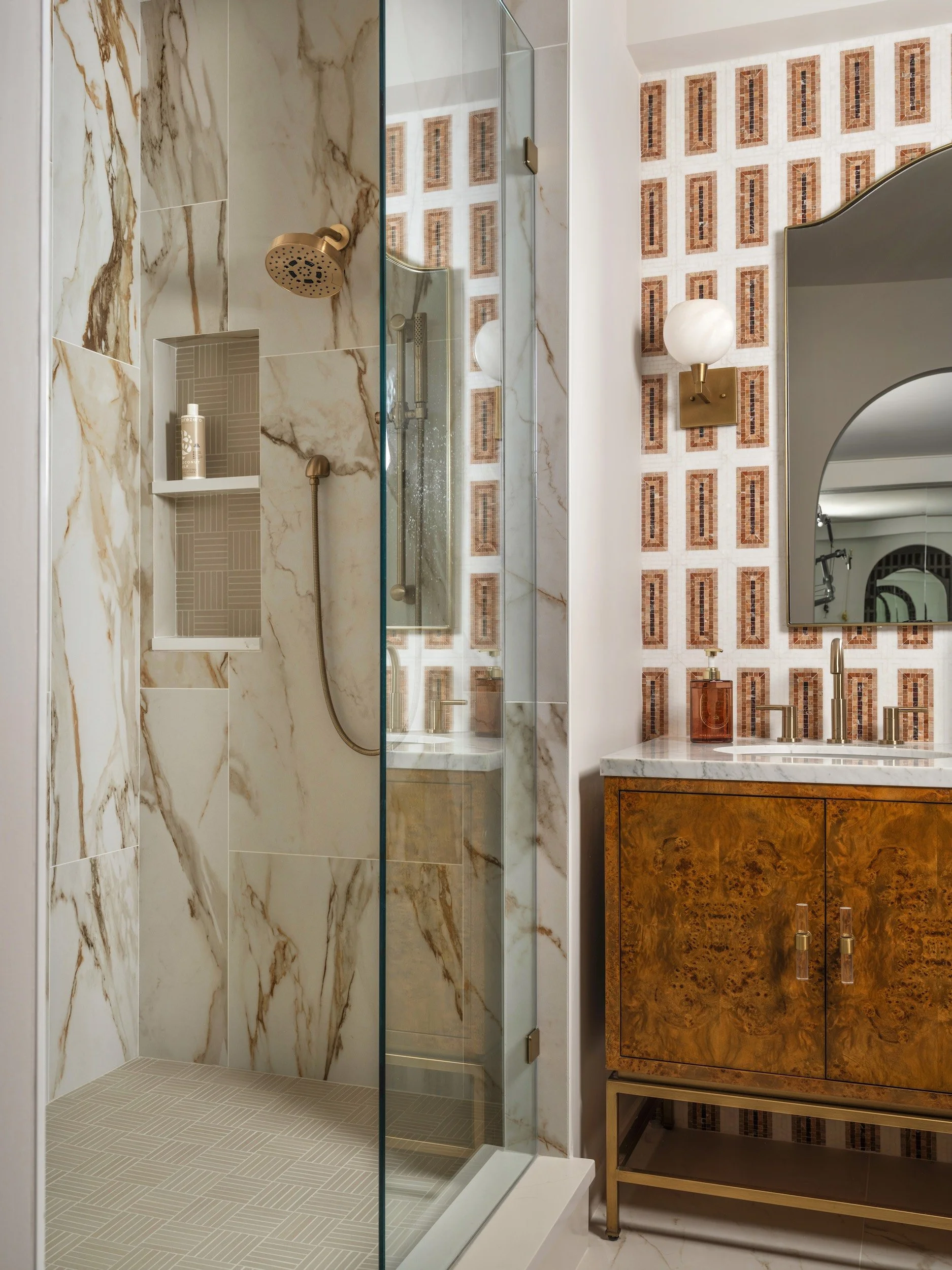 Marble shower with dual brass rain heads and herringbone floor, designed by Luxe Style Studio