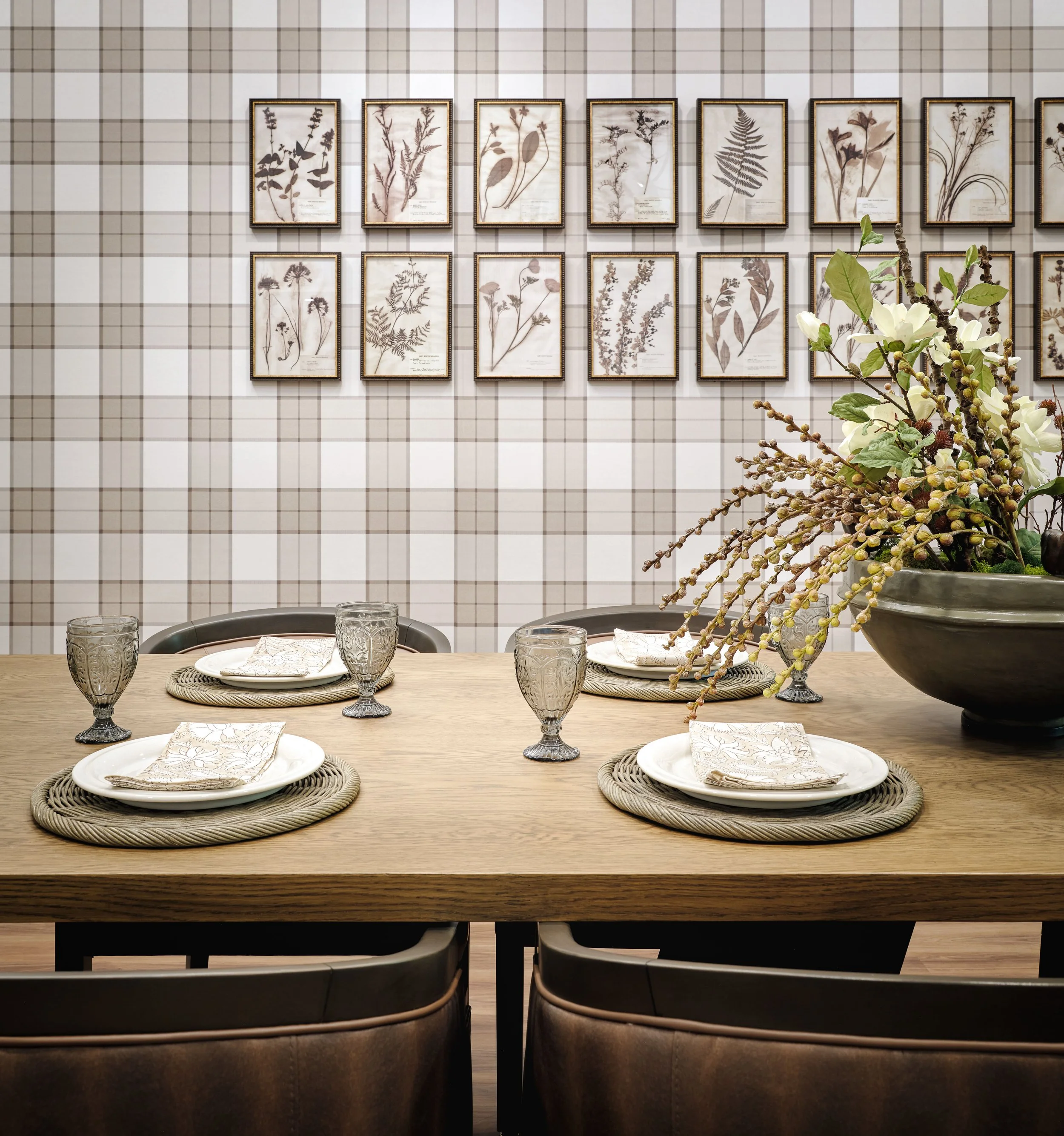 Thistle & Oak private dining table with botanical artwork, woven placemats, plaid wallcovering, and an organic floral centerpiece, designed by Ashley Schneider