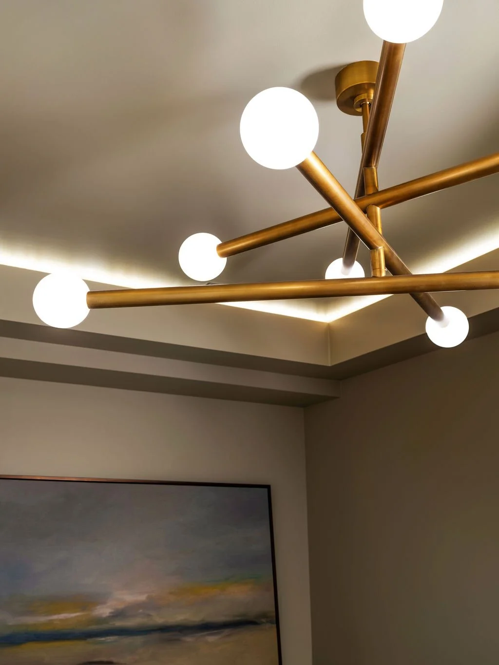 Close-up detail of brass sputnik chandelier with globe bulbs and LED cove ceiling lighting in moody sitting room, interior design by Luxe Style Studio