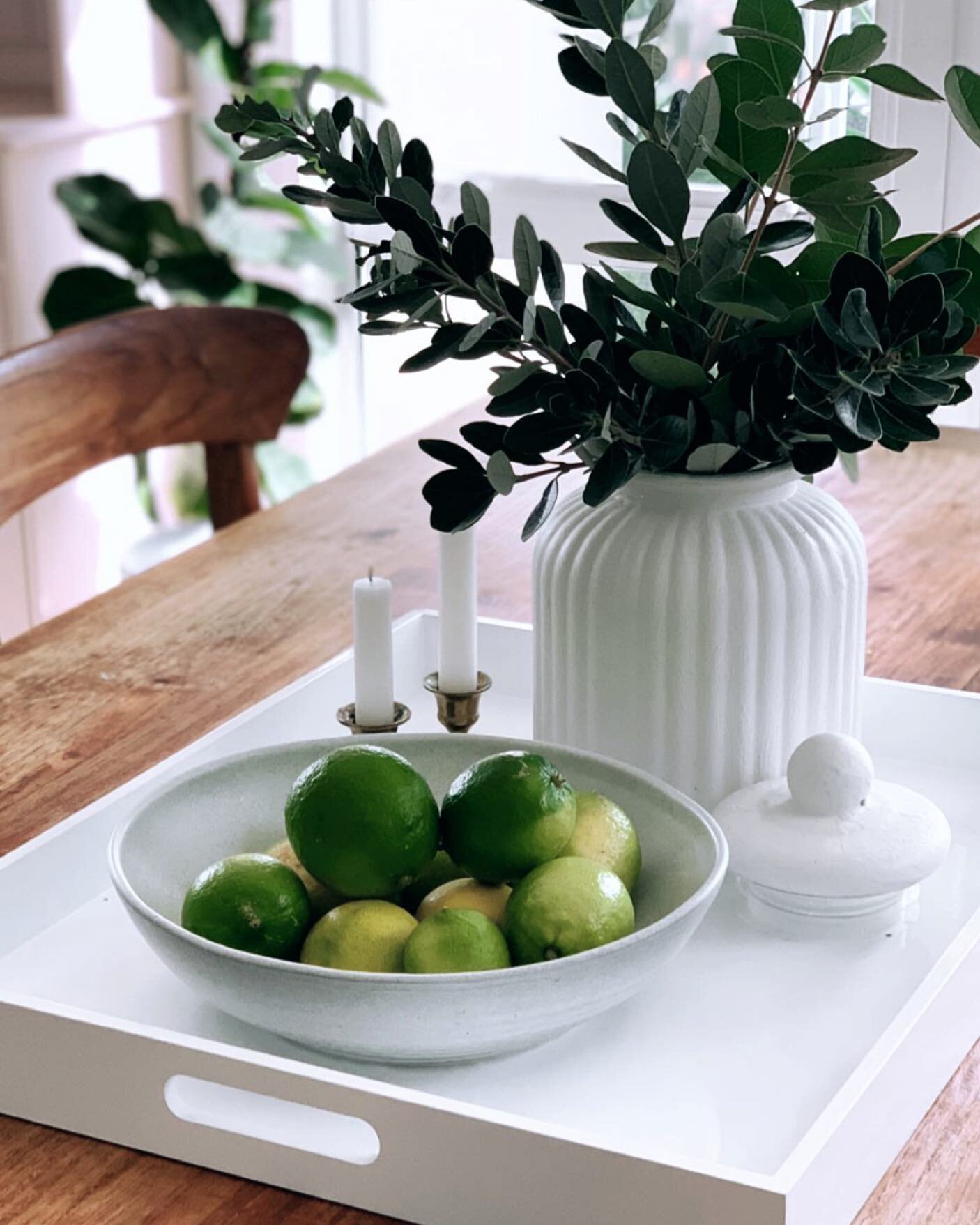 I raided the garden today to put together this simple dining table display on my new @freedom_nz Lacquer White Tray.  Feijoa leaves and limes off the tree, then added a bowl I used for serving and a glass vase which I have previously painted white to