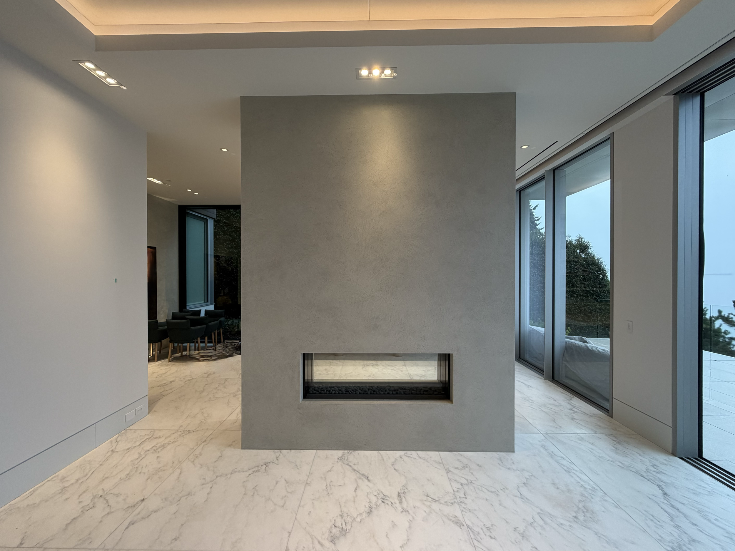 A monolithic-style plaster finish applied to this  striking four-sided fireplace finished in a custom-coloured, five-coat lime plaster. Each layer was applied with care and precision. The result is an artistic, refined finish that adds depth and life