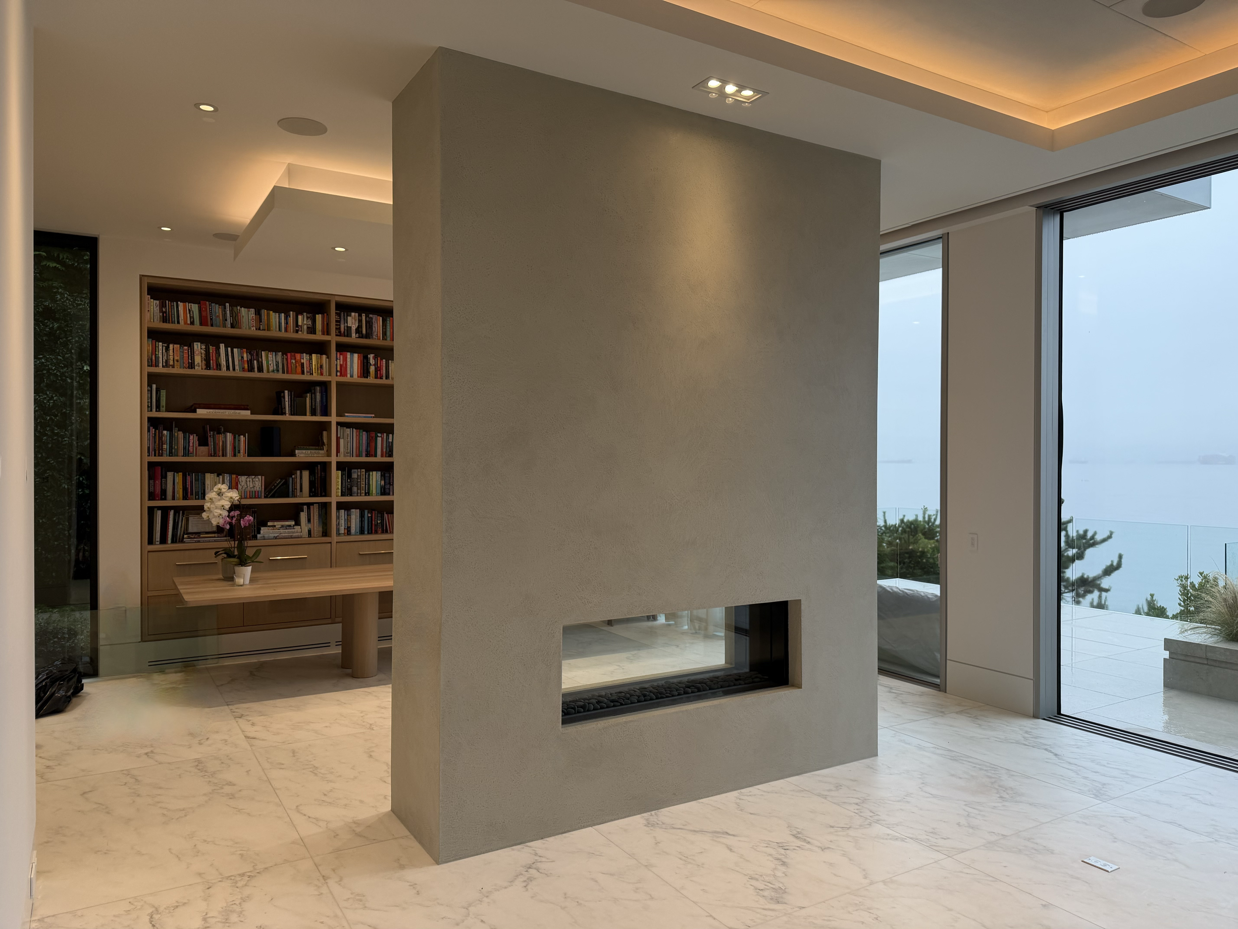 A monolithic-style plaster finish applied to this  striking four-sided fireplace finished in a custom-coloured, five-coat lime plaster. Each layer was applied with care and precision. The result is an artistic, refined finish that adds depth and life