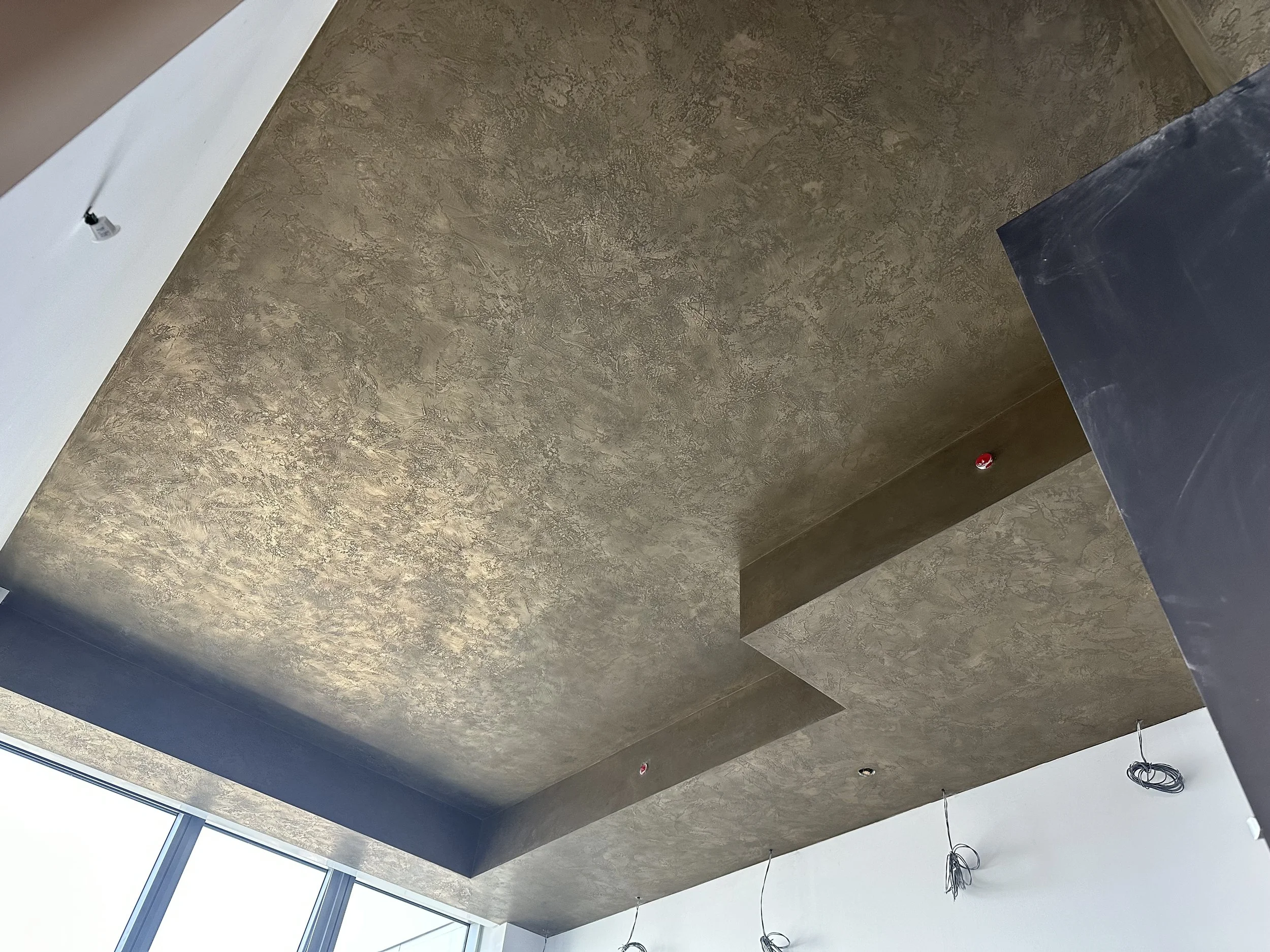 This ceiling is crafted from 100% bronze, brass, and stainless-steel Liquid Metal (LMFX), finished with a trowel-overlap pattern. The result is a striking, reflective surface with sculptural depth and a dynamic, tactile quality that elevates the enti