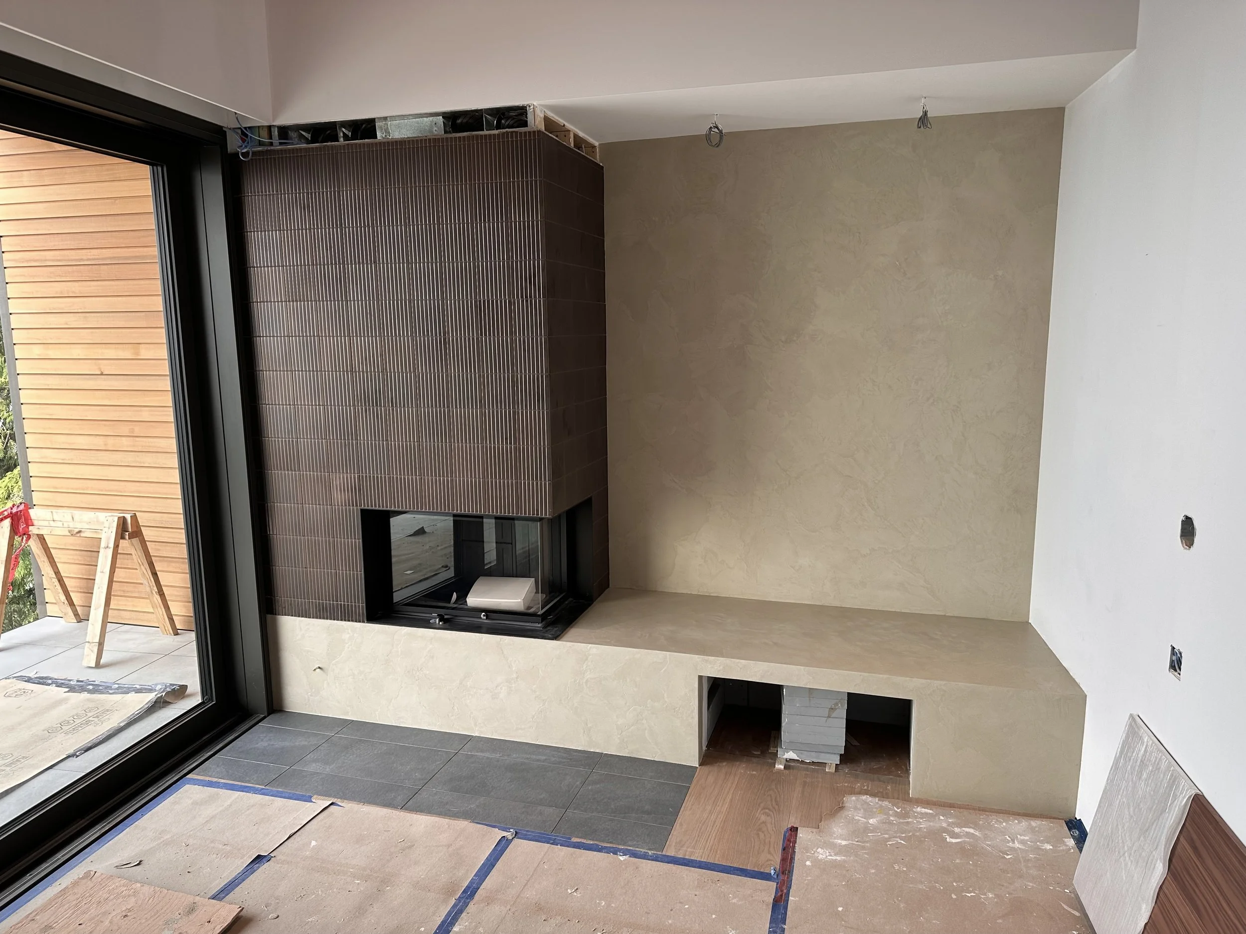 Micro-cement fireplace wall and hearth, finished with an organic, hand-applied texture that brings warmth and depth to the space. The surface feels both natural and tactile, catching light beautifully while adding a subtle, sculptural quality to the
