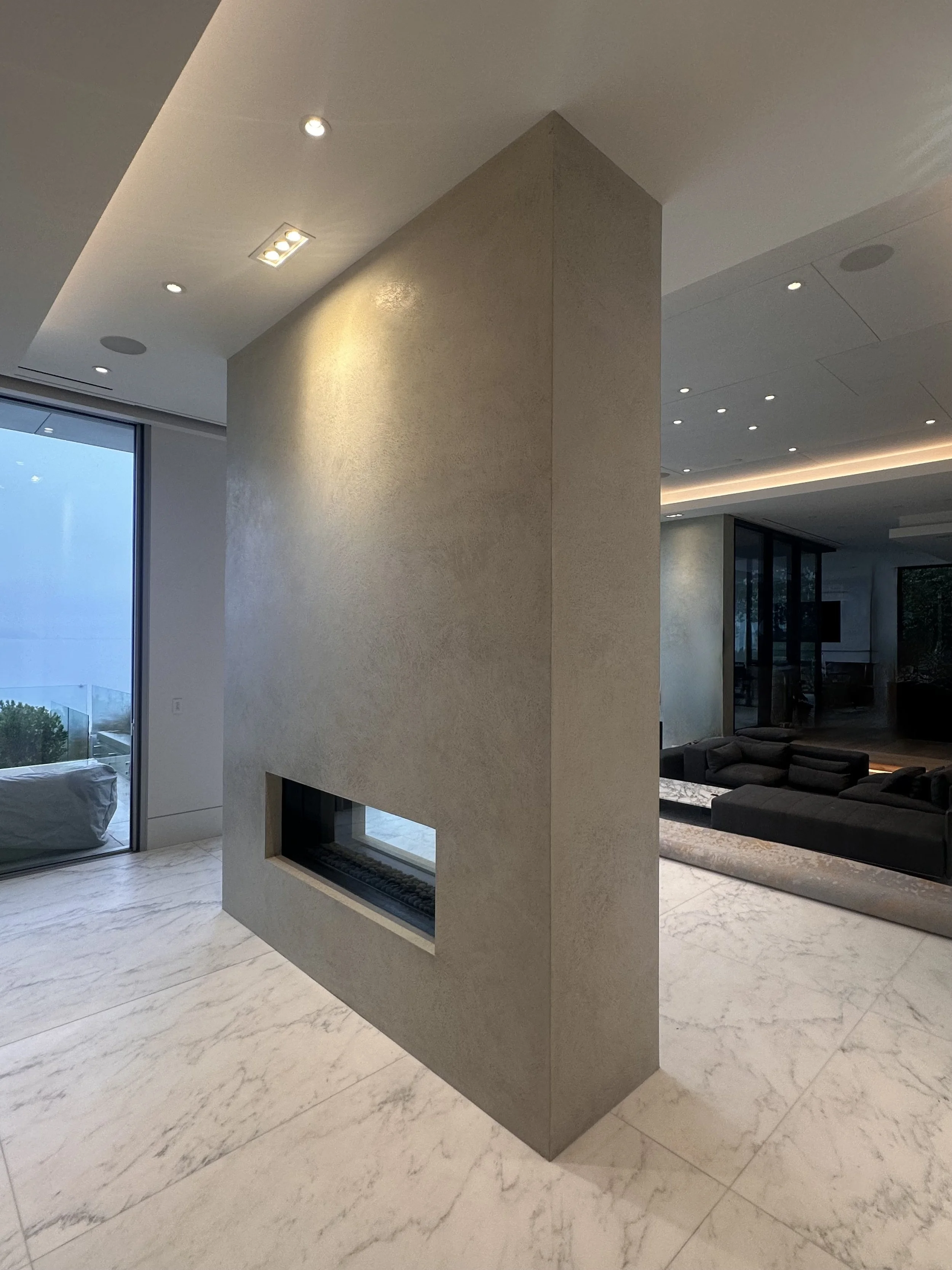 A monolithic-style plaster finish applied to this striking four-sided fireplace finished in a custom-coloured, five-coat lime plaster. Each layer was applied with care and precision. The result is an artistic, refined finish that adds depth and life 