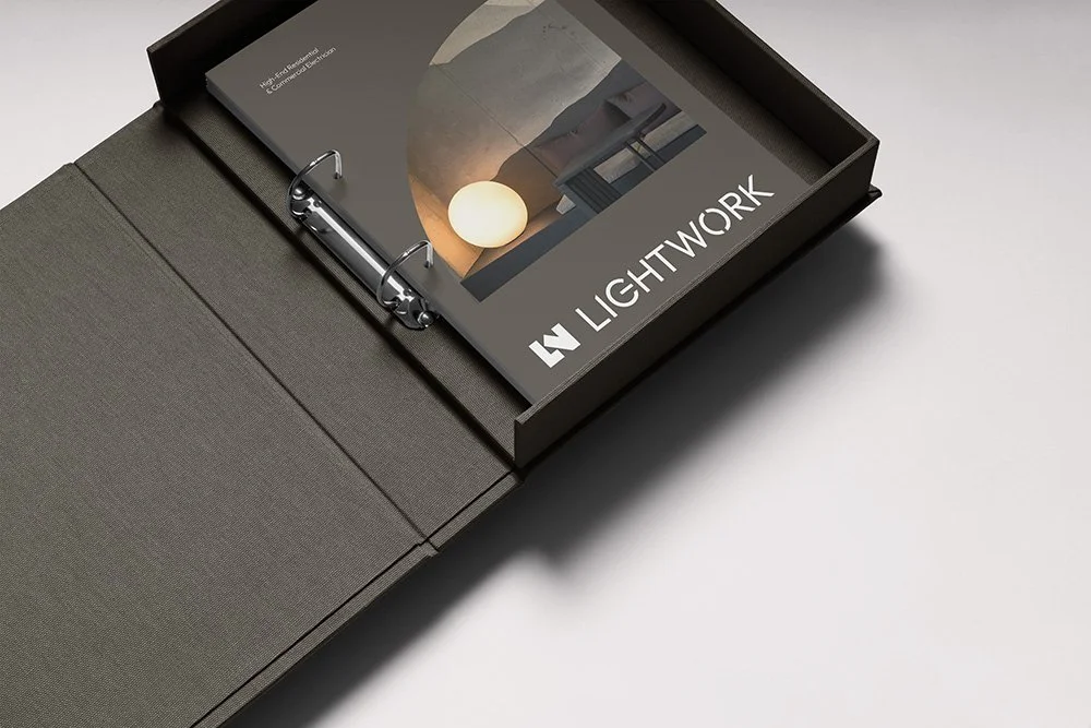 Open gray binder with a binder clip, containing marketing materials for Lightwork.