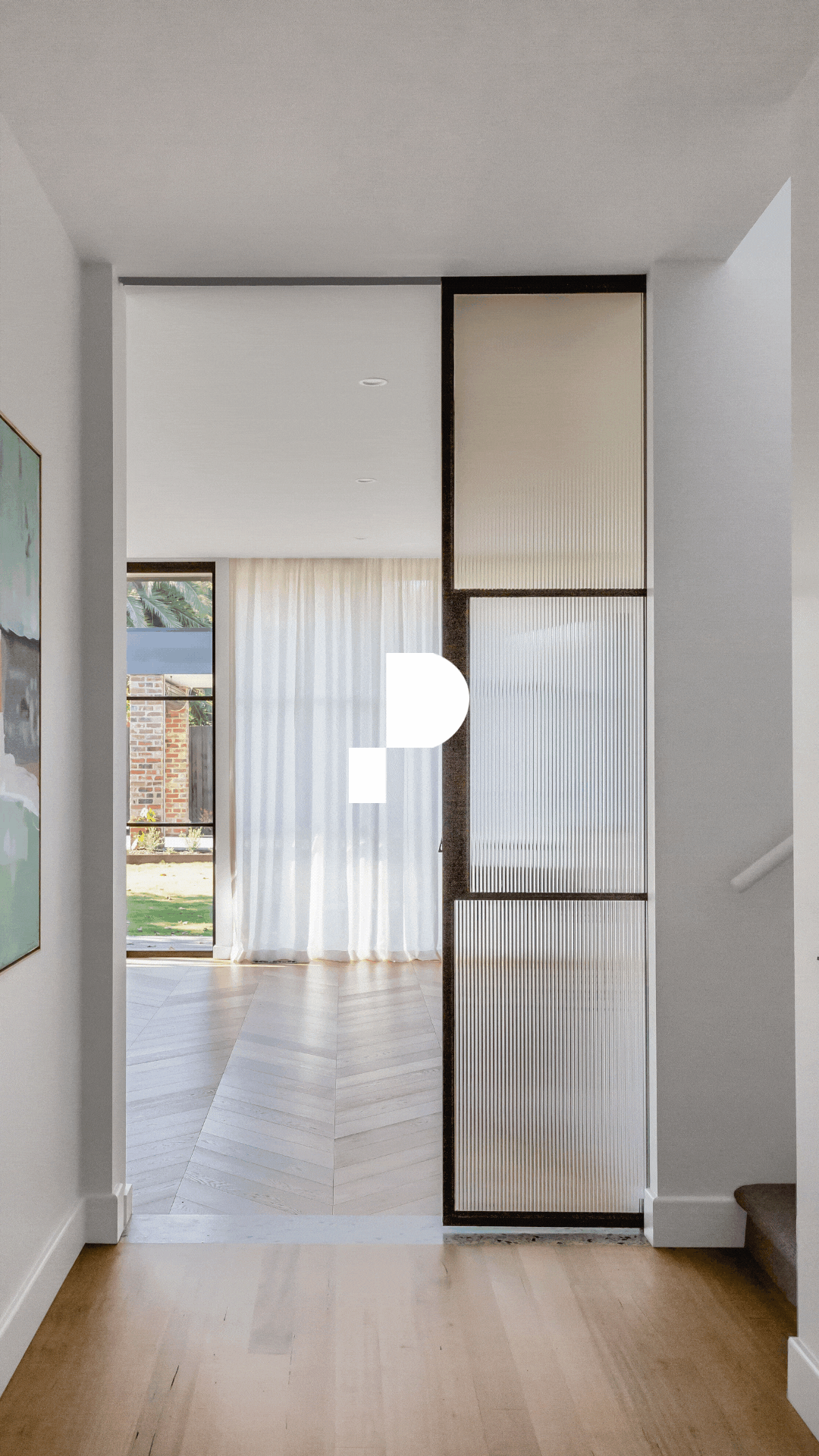 Interior of a modern house with a sliding glass door, sheer curtains, and a decorative partition with frosted glass panels.