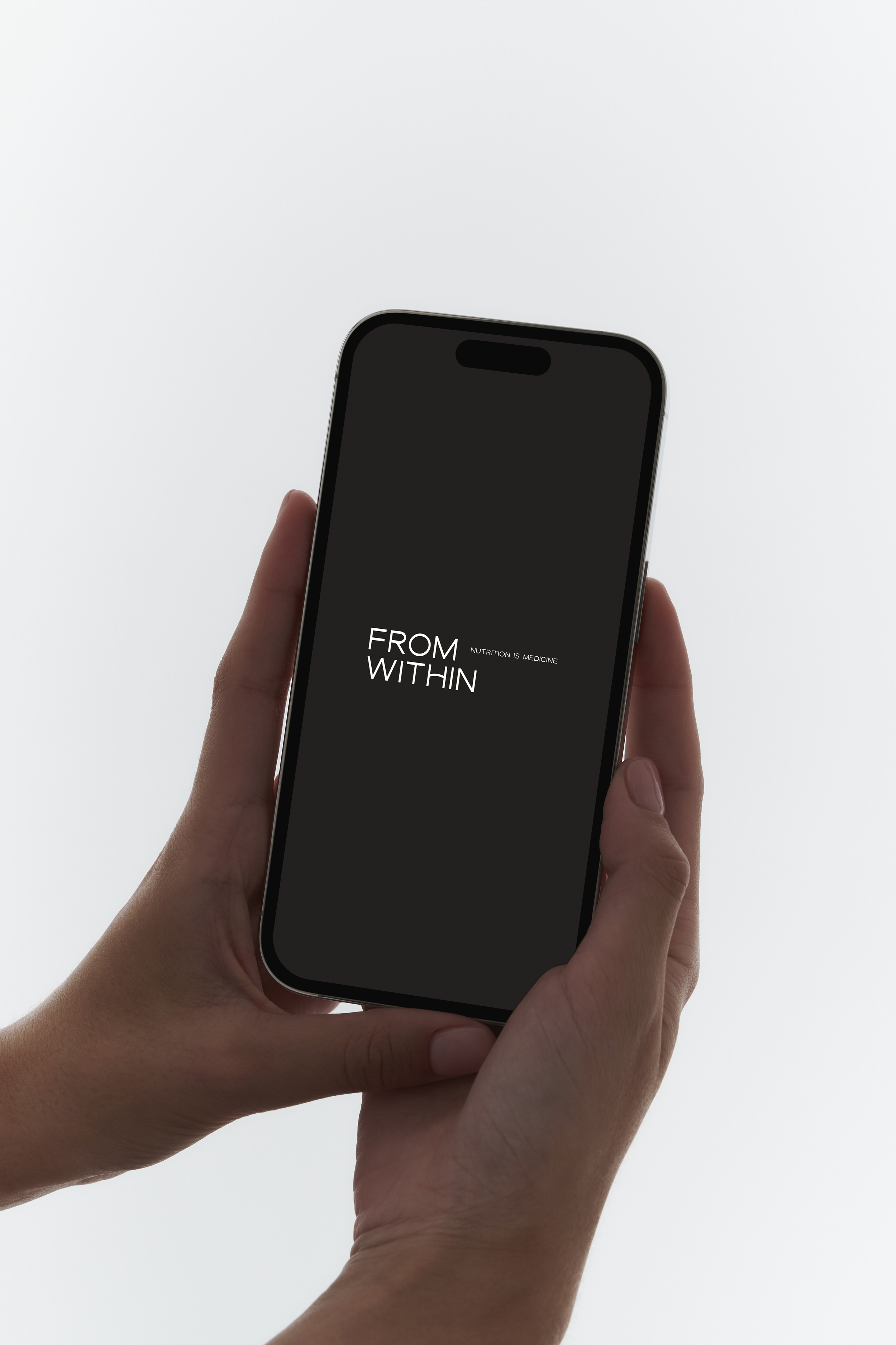 A person holding a smartphone displaying the text 'FROM WITHIN' and 'NUTRITION IS MEDICINE' on a black background.