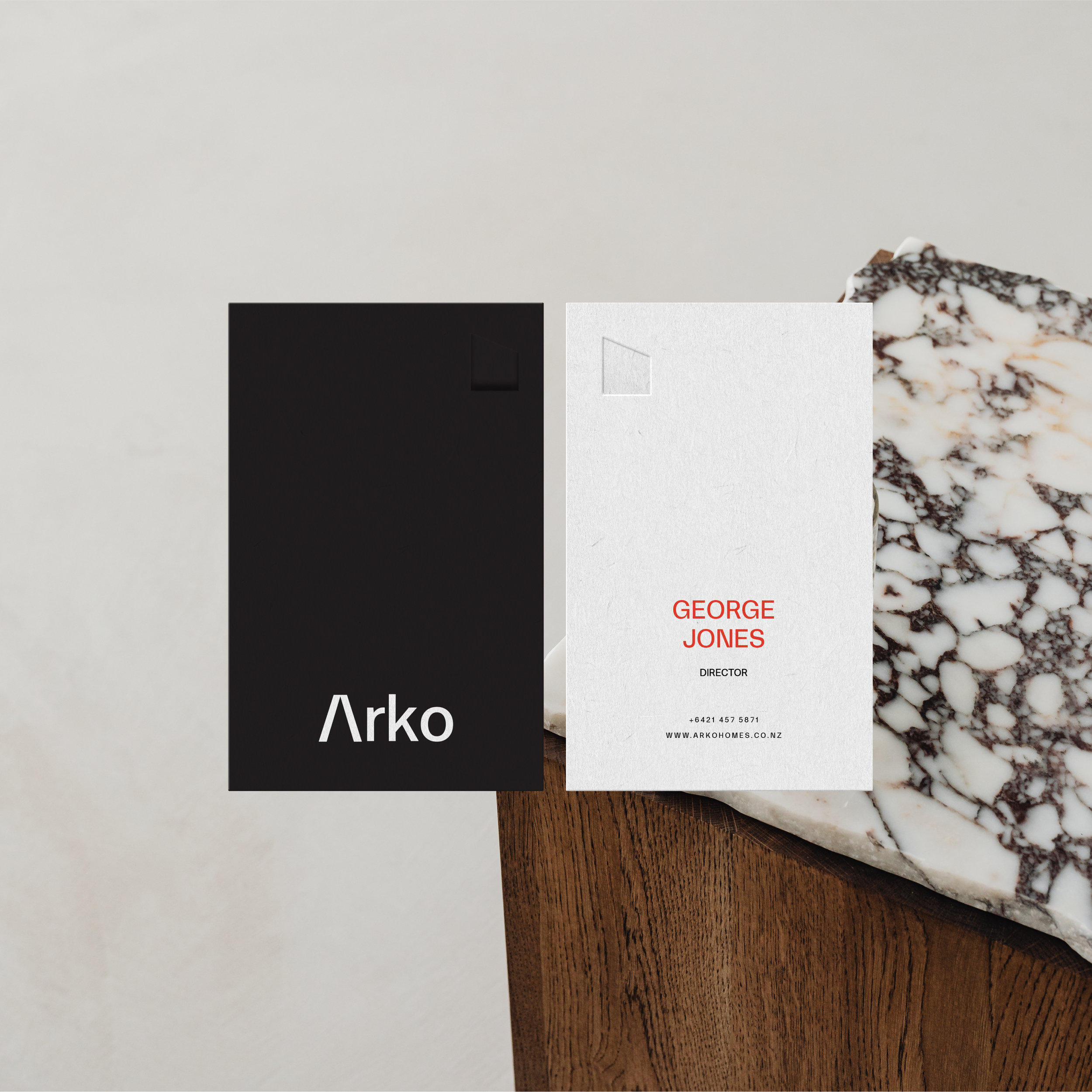 An iPhone with a black frame on a red and white surface, displaying a website for Arko with a kitchen image and partial logo text.
