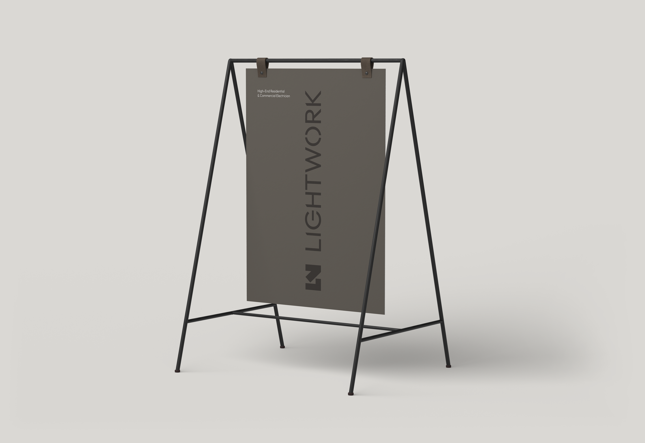 A black A-frame sidewalk sign with a large vertical dark gray poster that has the words 'IN LIGHTS' and smaller text reading 'High-End Residential & Commercial Electrician' on a plain light background.