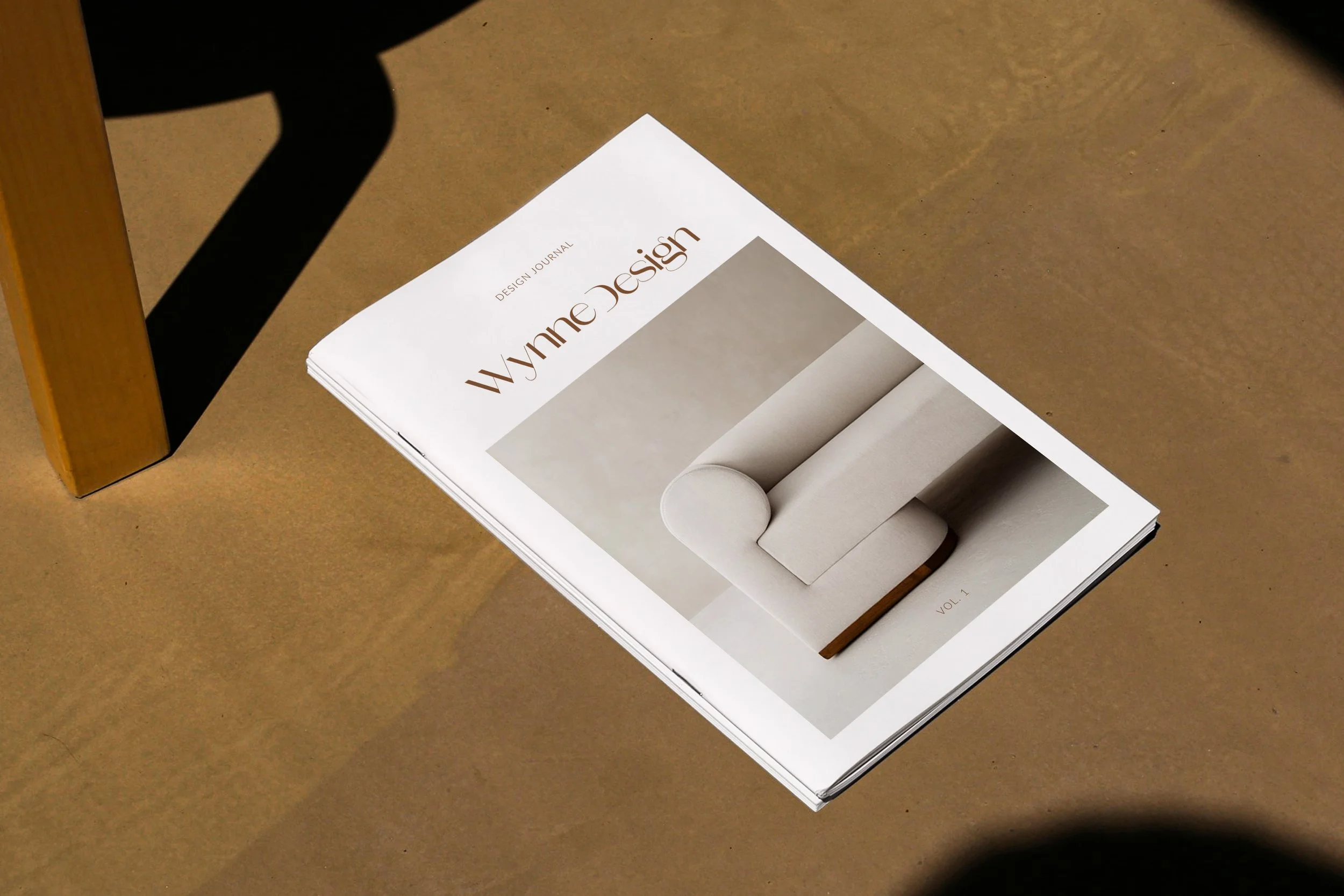 Design journal titled 'Wynne Design' with a picture of a beige sofa on the cover, placed on a brown table.