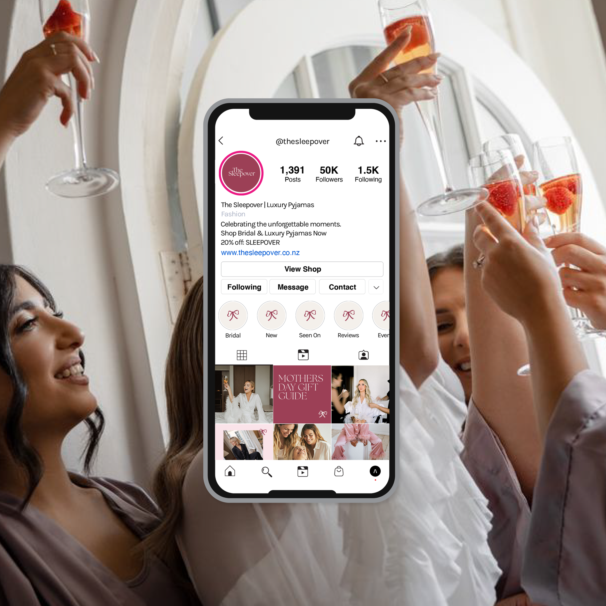 Group of women celebrating with champagne glasses in front of a mirror, with an iPhone displaying The Sleepover Instagram profile in the foreground.
